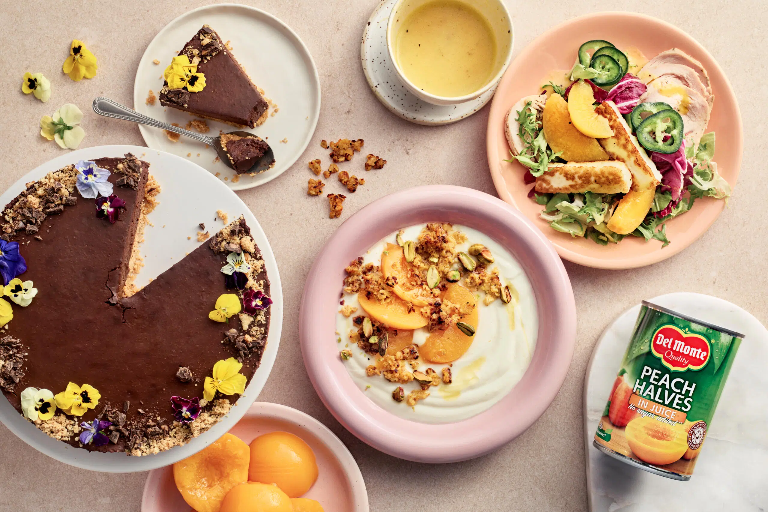 Kuvassa suklaa-persikkakakku, persikkainen jogurttiannos ja kana-persikkasalaatti sekä tölkki Del Monte persikanpuolikkaita mehussa