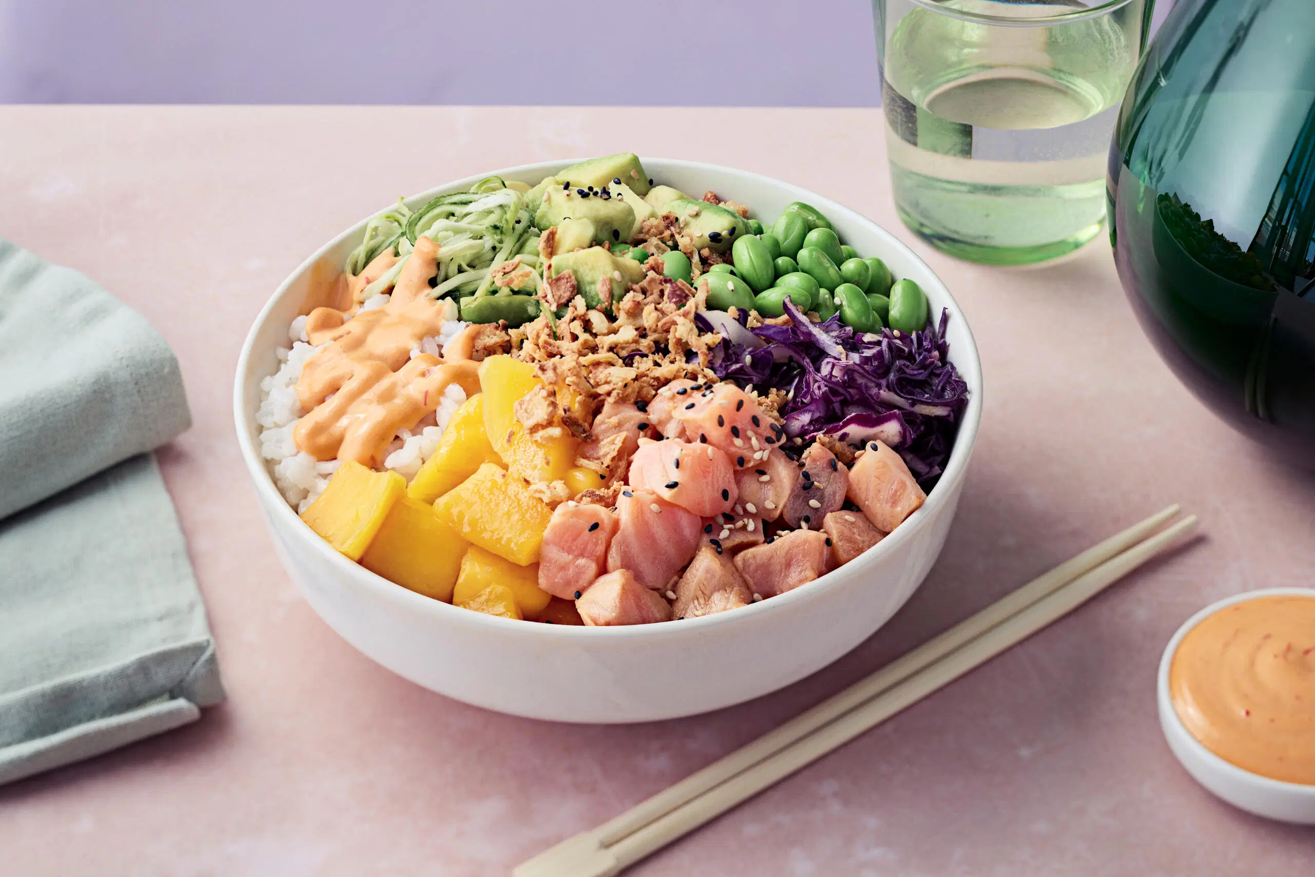 Kulhossa värikäs poke bowl -annos, jossa lohta, kasviksia ja riisiä.