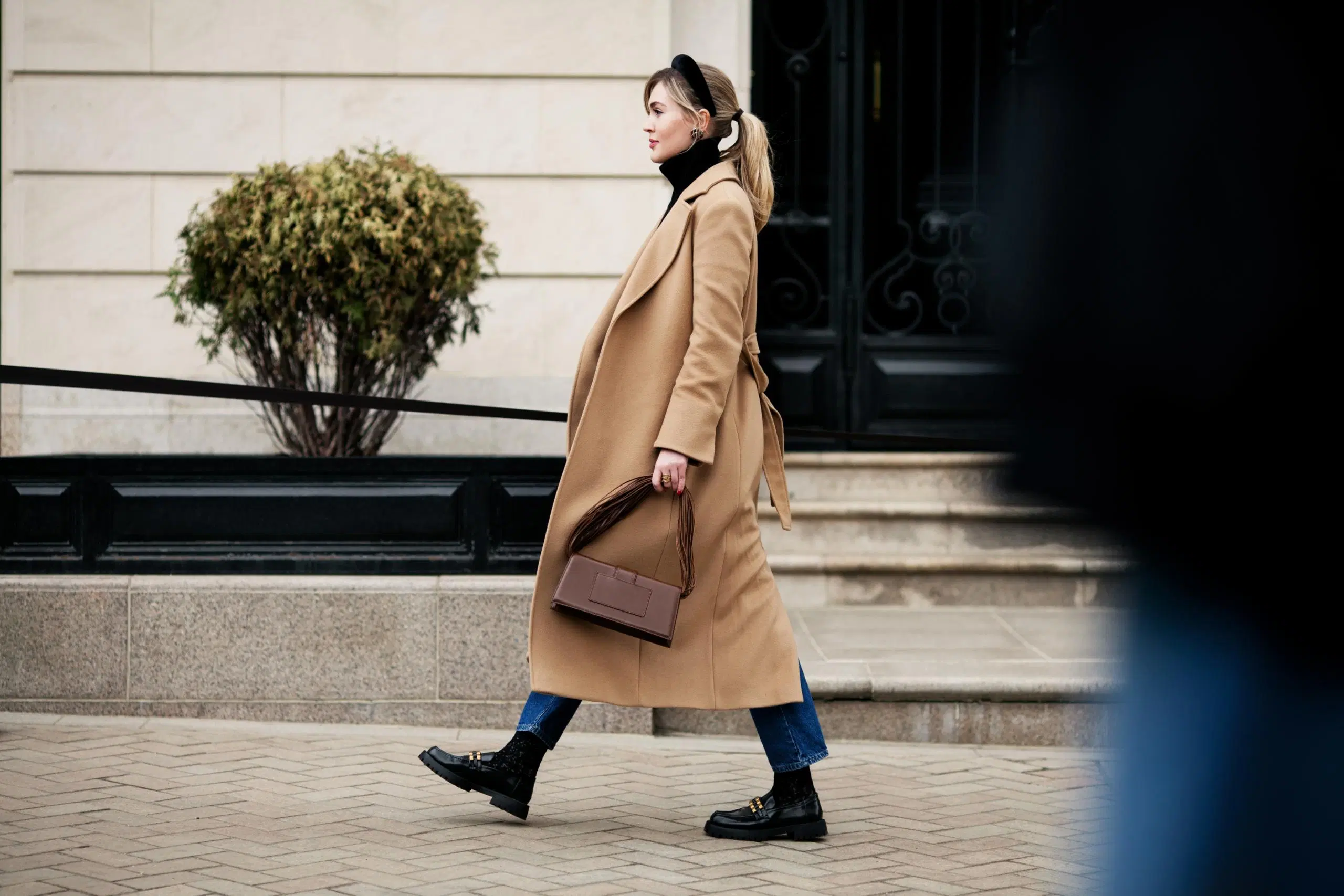 Tyylikkäästi pukeutunut nainen kävelee kadulla