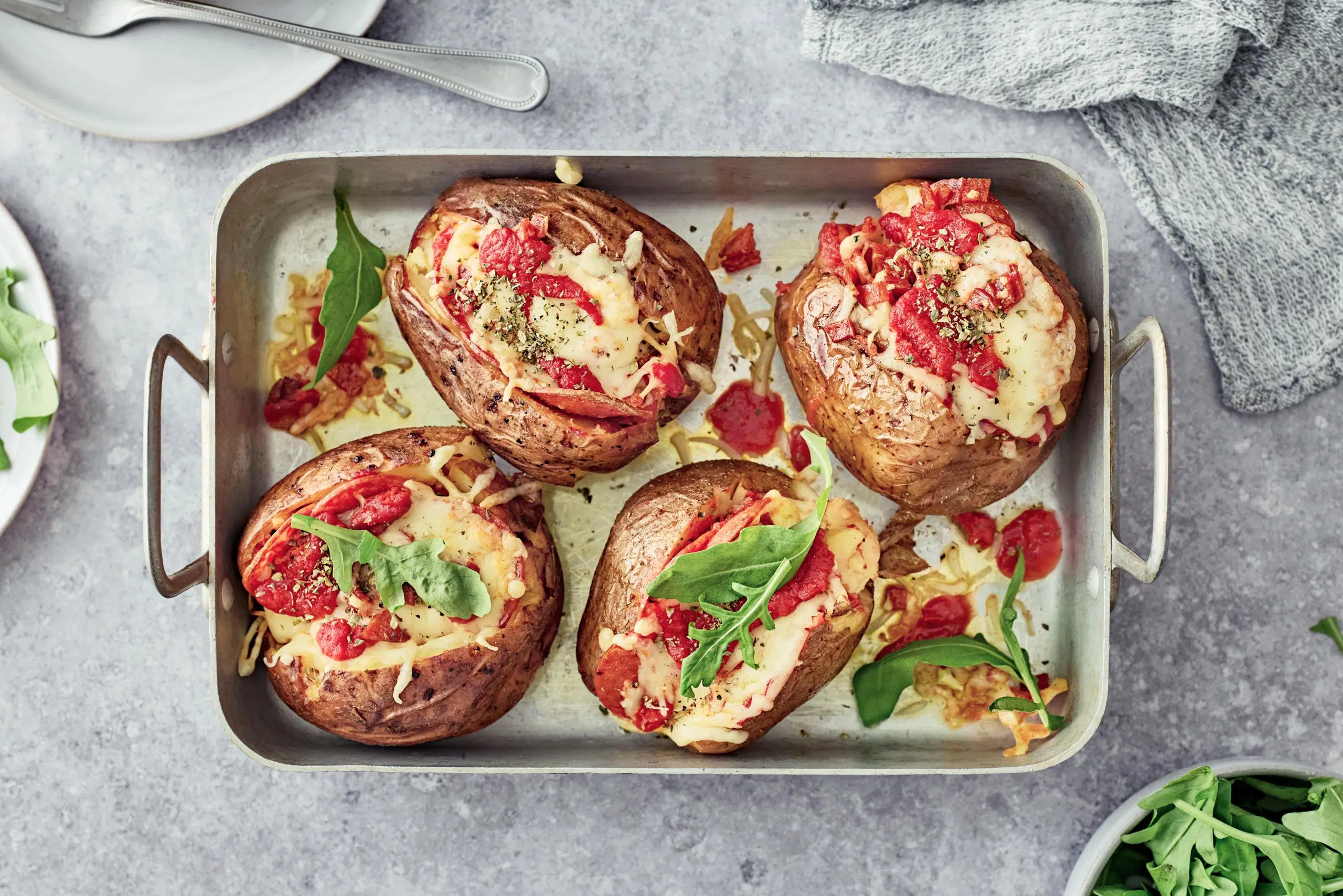 Uuniperunat pizzatäytteellä uunivuoassa.