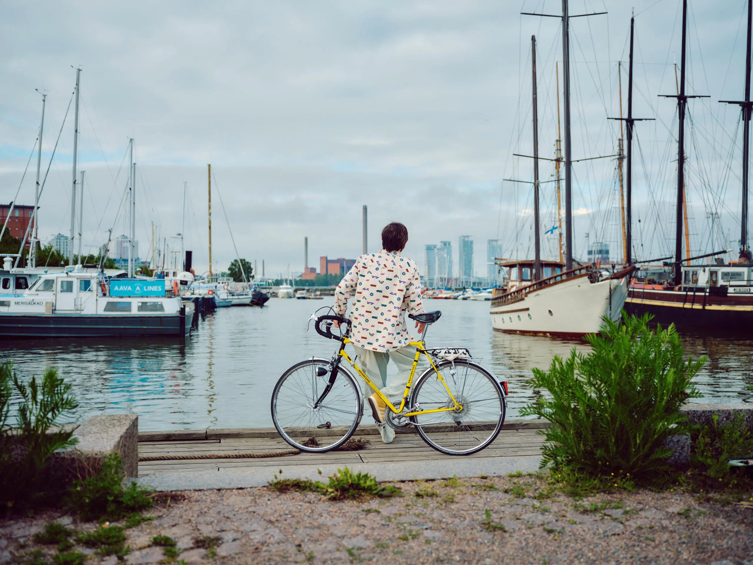 Henkilö katselee Helsingin Pohjoisrannassa merelle, taustalla Helsingin Kalasataman tornit
