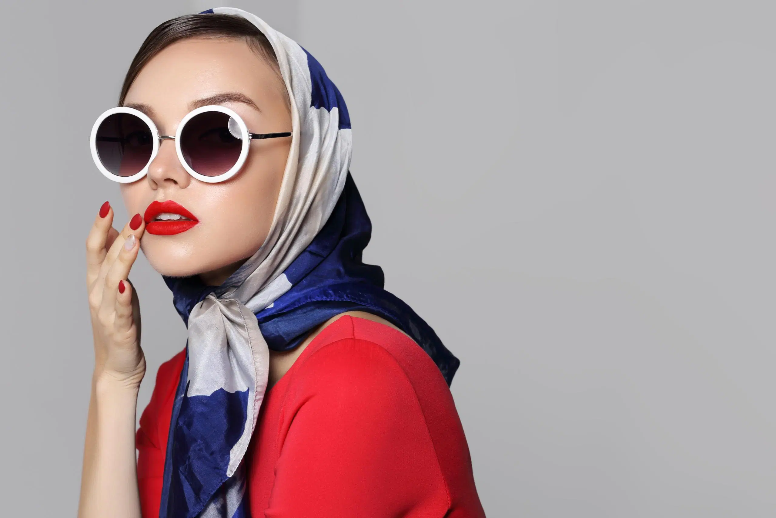 Nainen, jolla päässään isot aurinkolasit ja silkkihuivi