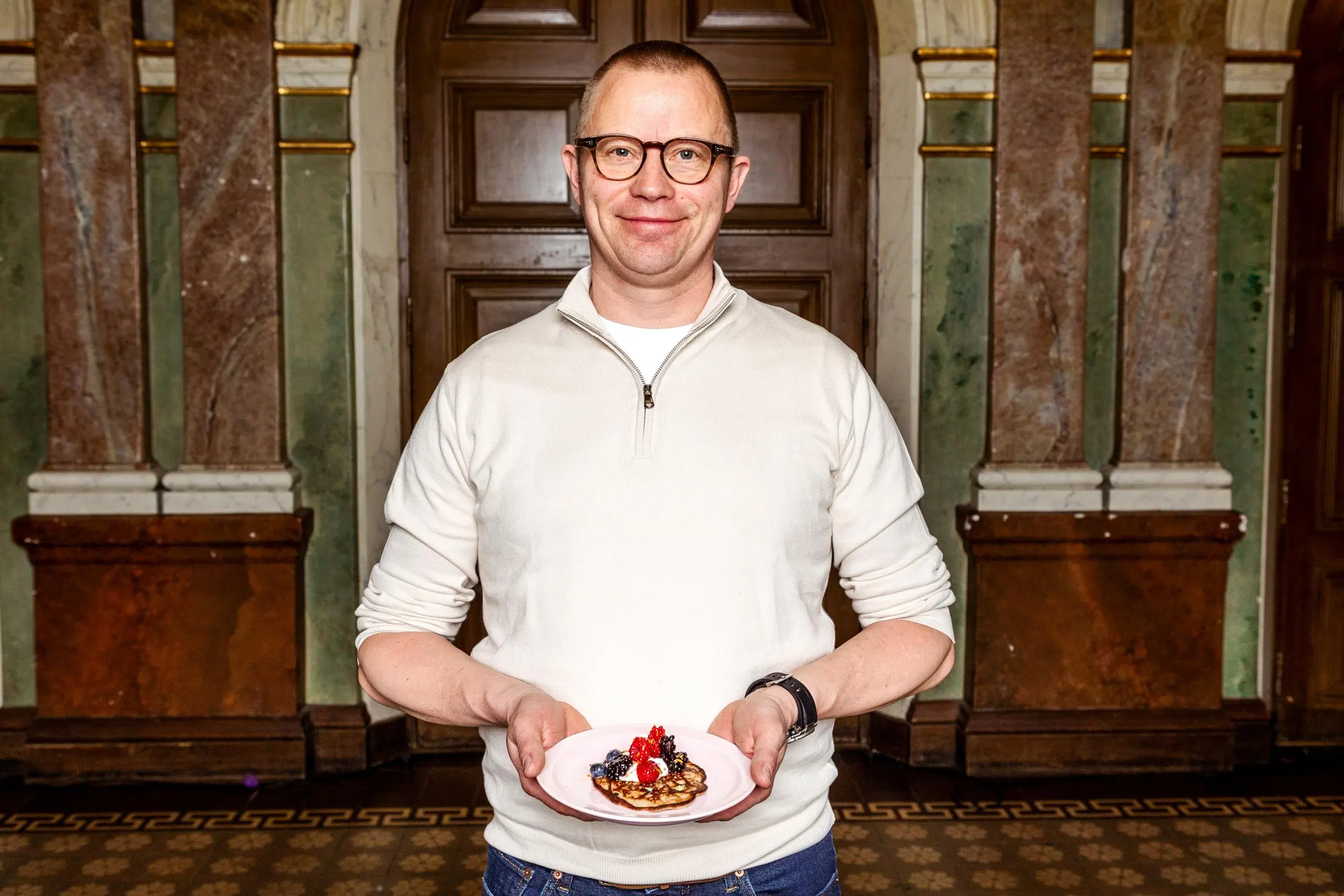 Samuli Wirgentius käsissään lautanen, jolla on lettu kermavaahdolla ja marjoilla