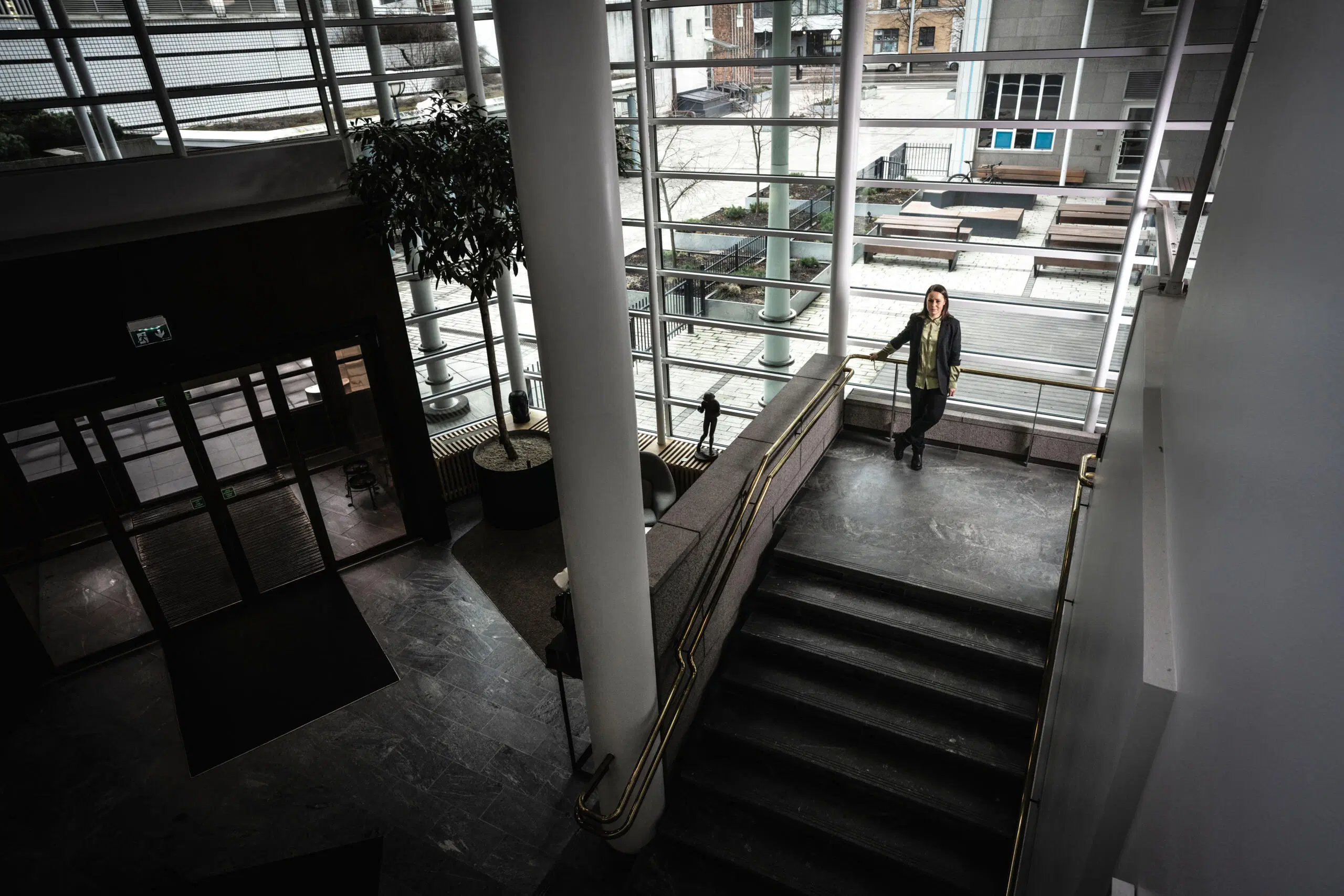 Nainen seisoo suuryrityksen aulatilan portaikolla