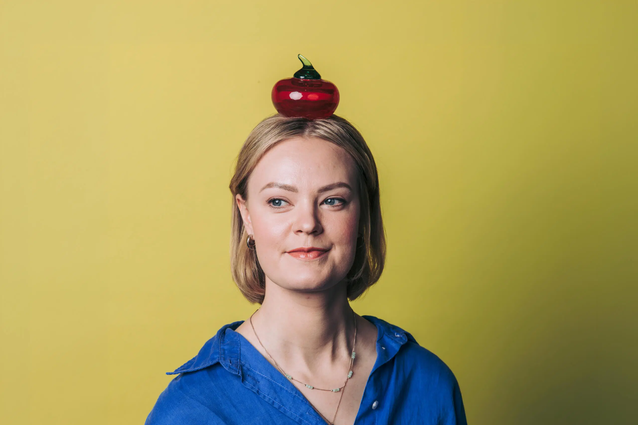 Potretti naisesta, jonka pään päällä on lasiomena.