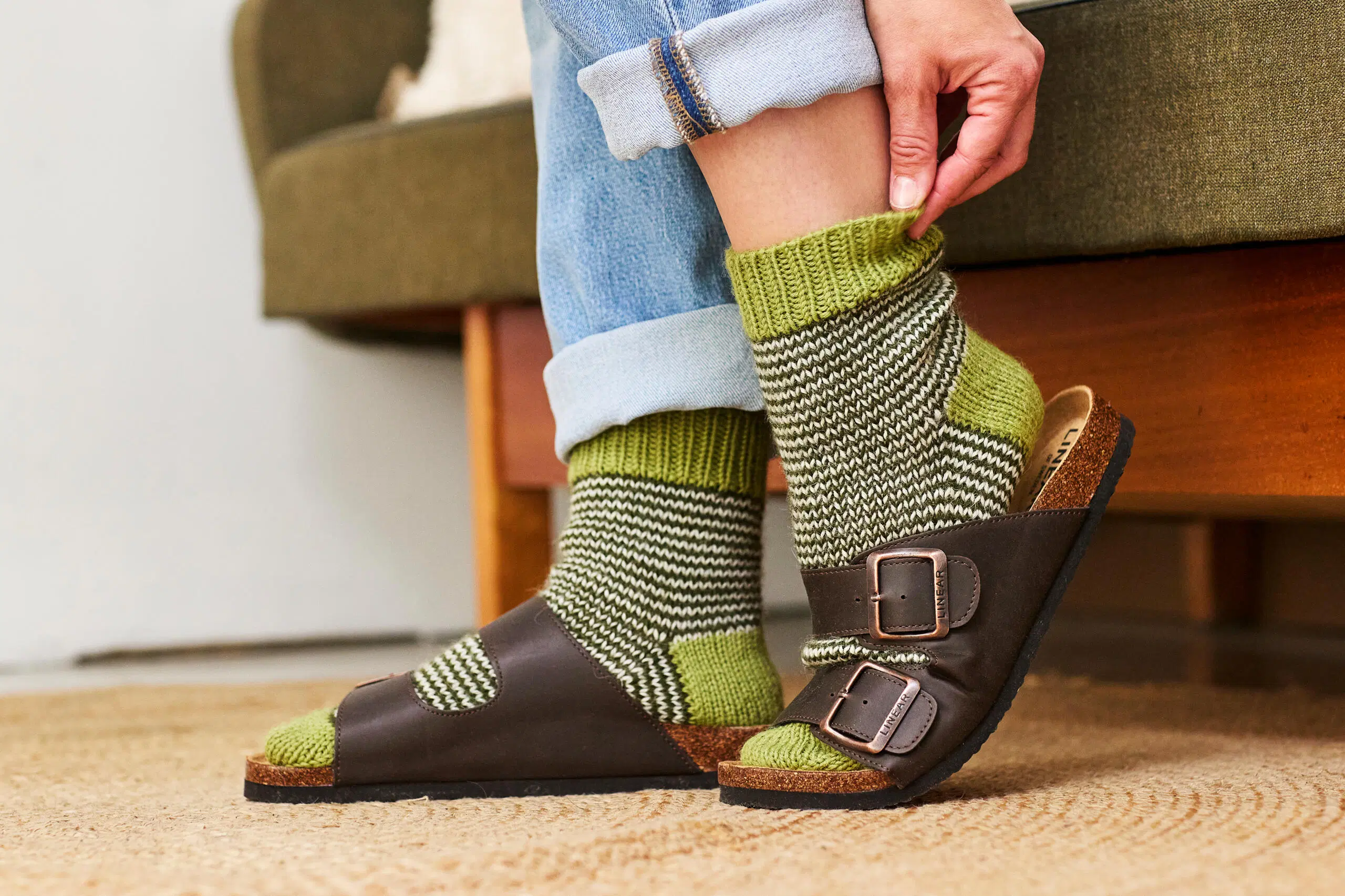 Naisen jalat, jossa on vihreäraidalliset villasukat ja Birkenstock-sandaalit.