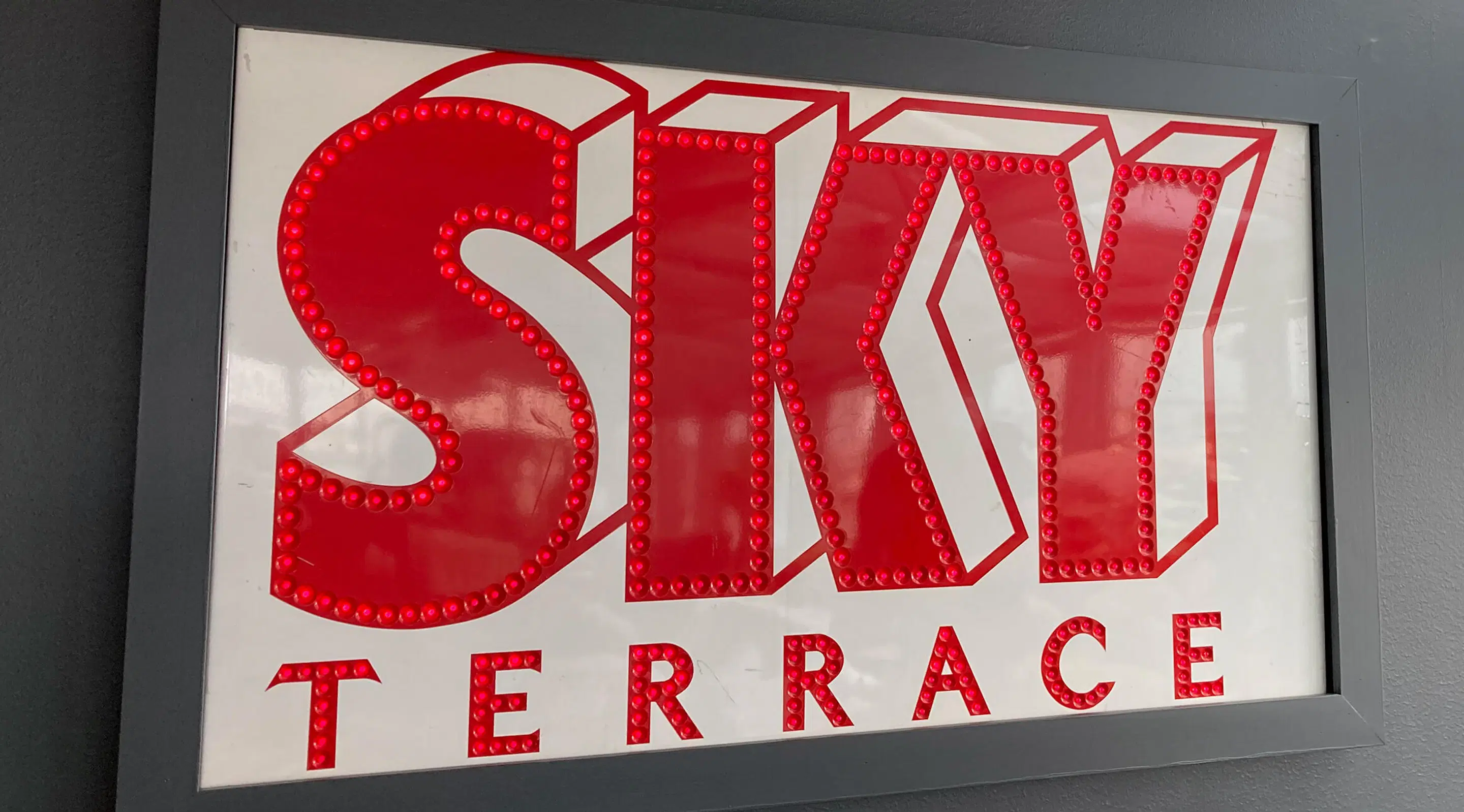 Red illuminated sign with decorative letters outlined with red beads.