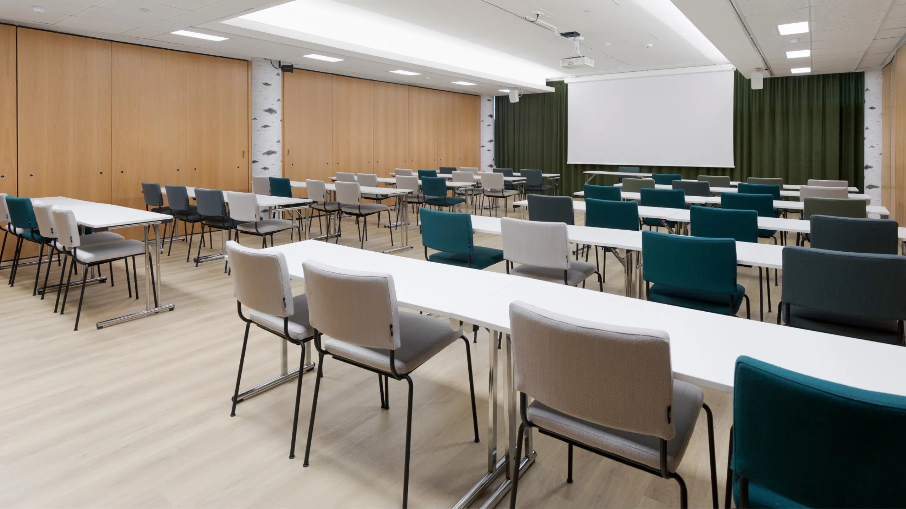 Modern conference room with light tables and turquoise and white chairs. Wood panels on walls and light flooring.