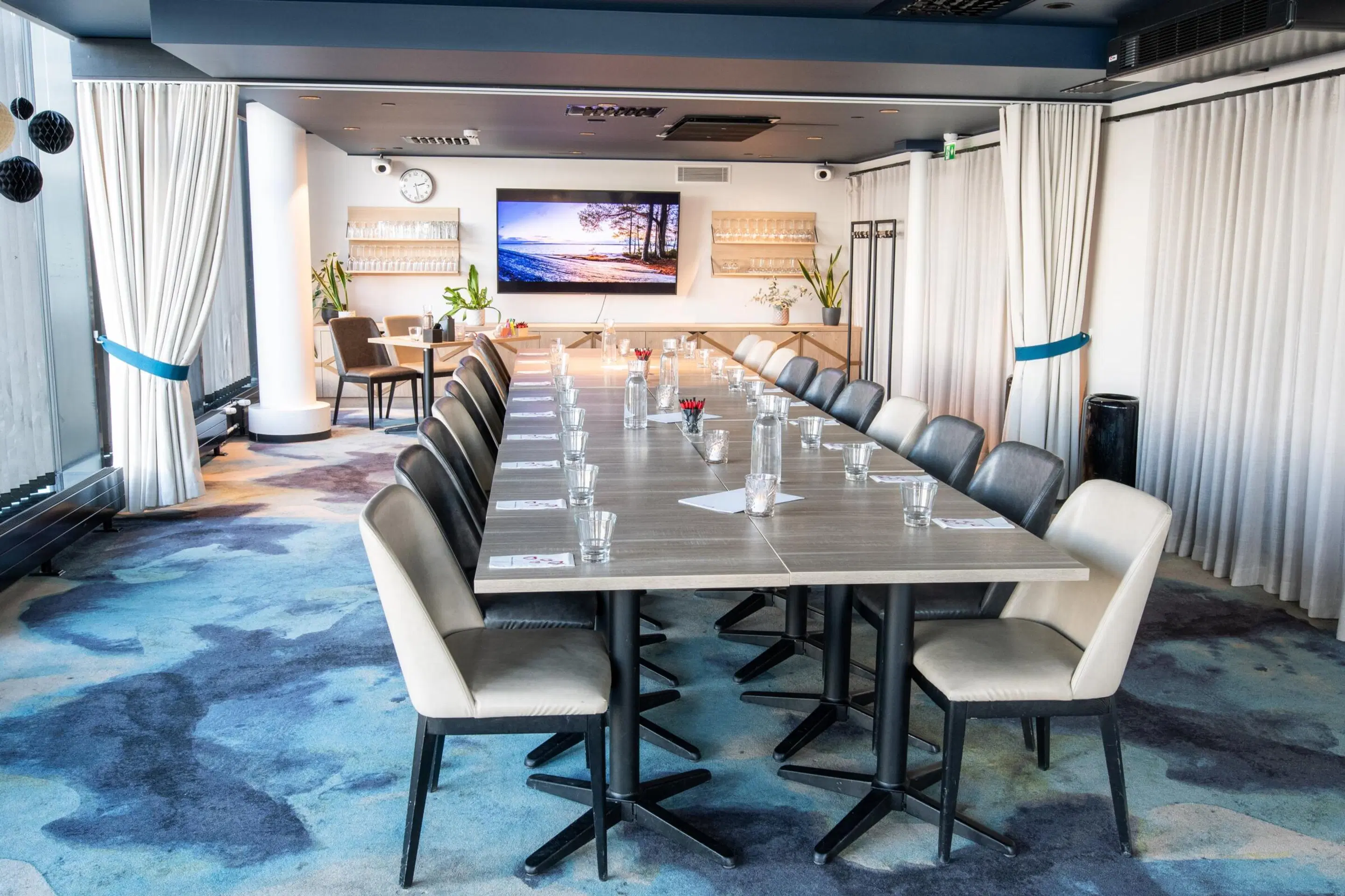 Meeting room with long conference table and leather-upholstered chairs. Room has low-pile carpet and overhead lighting.