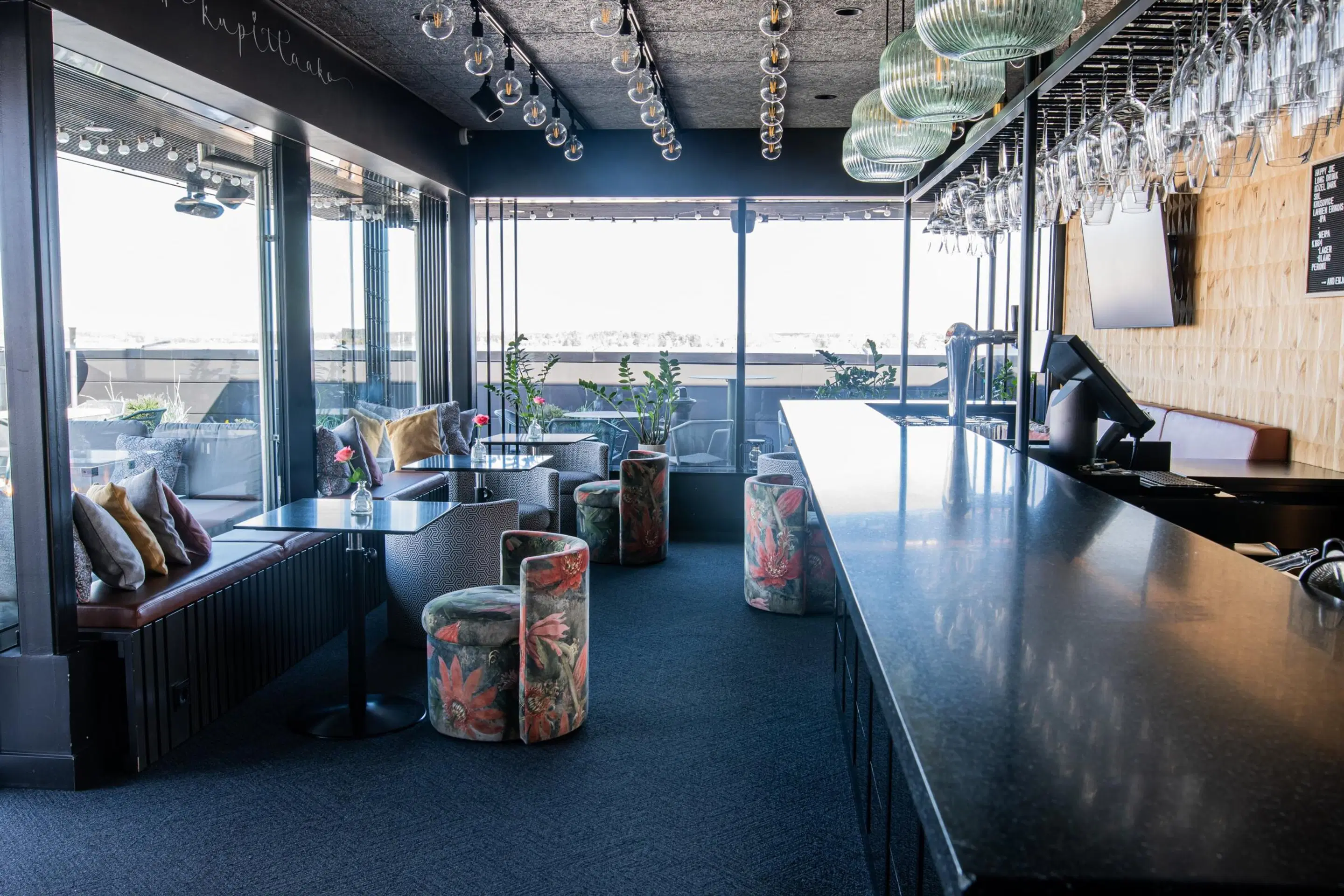 Kuppis Rooftop Bar sisätila, jossa pitkä baaritiski, istumapaikkoja ja näkymä terassille.
