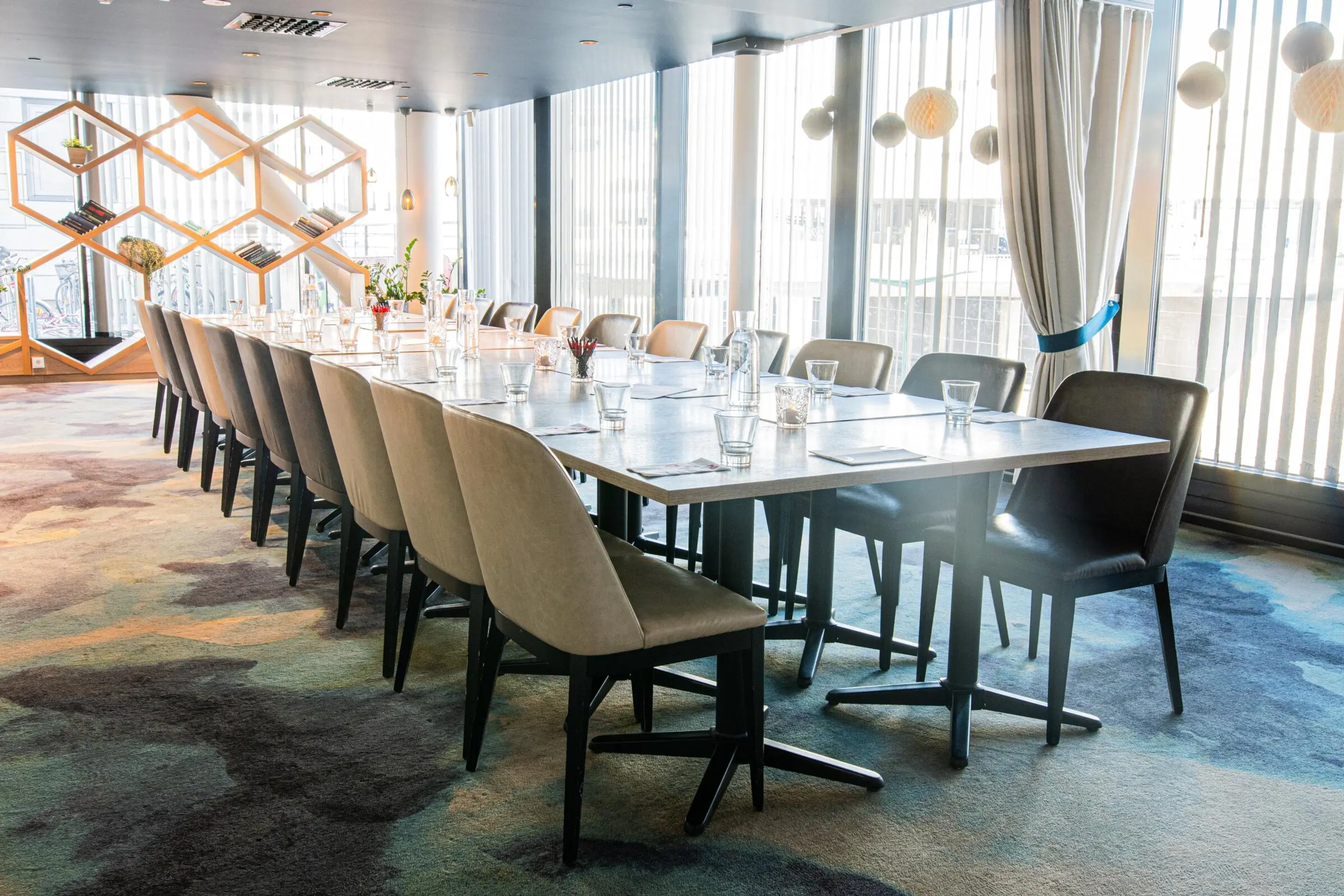 Bright meeting room with long table, upholstered chairs, and low-pile carpet.