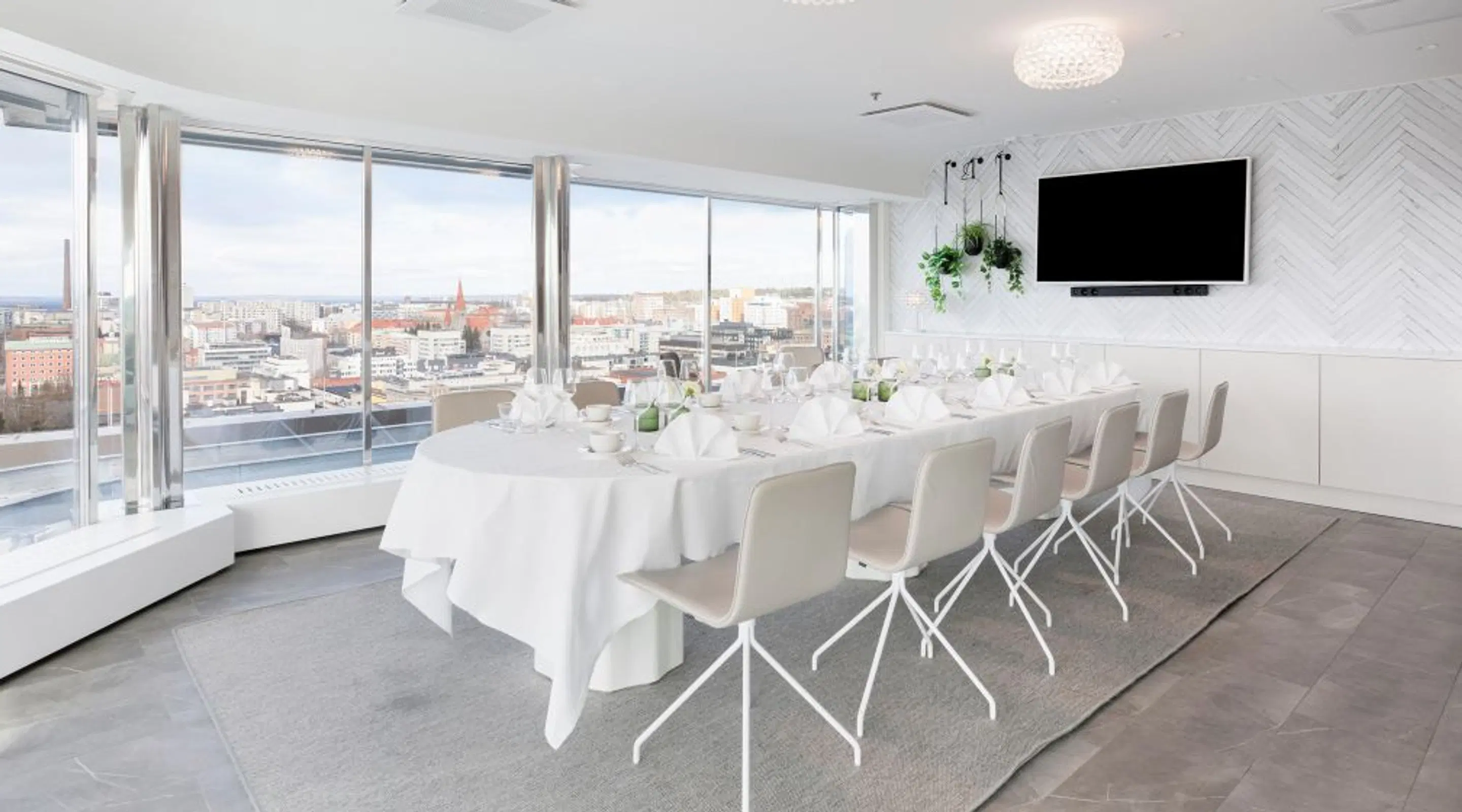 Bright meeting room with long table and white chairs, panoramic windows and hard floor.