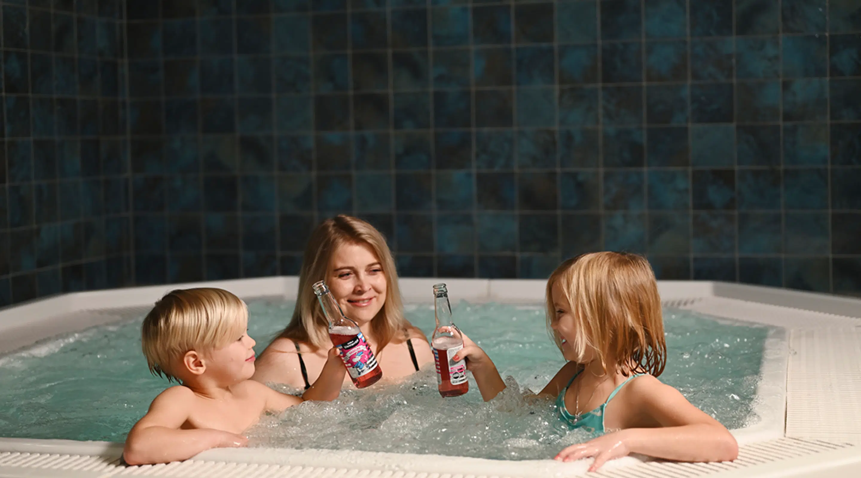 People enjoying beverages in a jacuzzi hot tub. Turquoise tile mosaic surrounds the water.