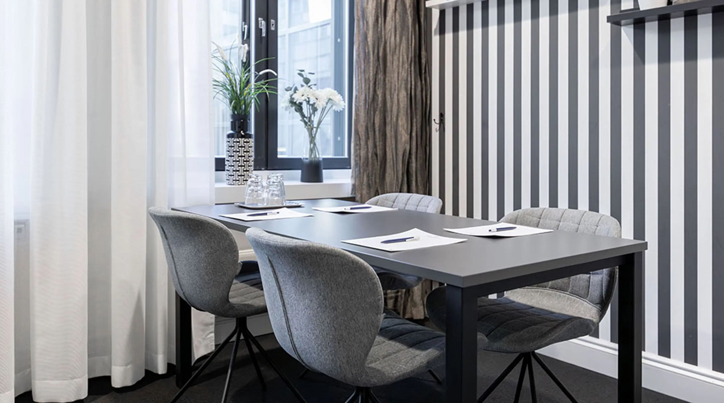 Modern meeting room with grey table and swivel chairs. Spacious entrance and level flooring.