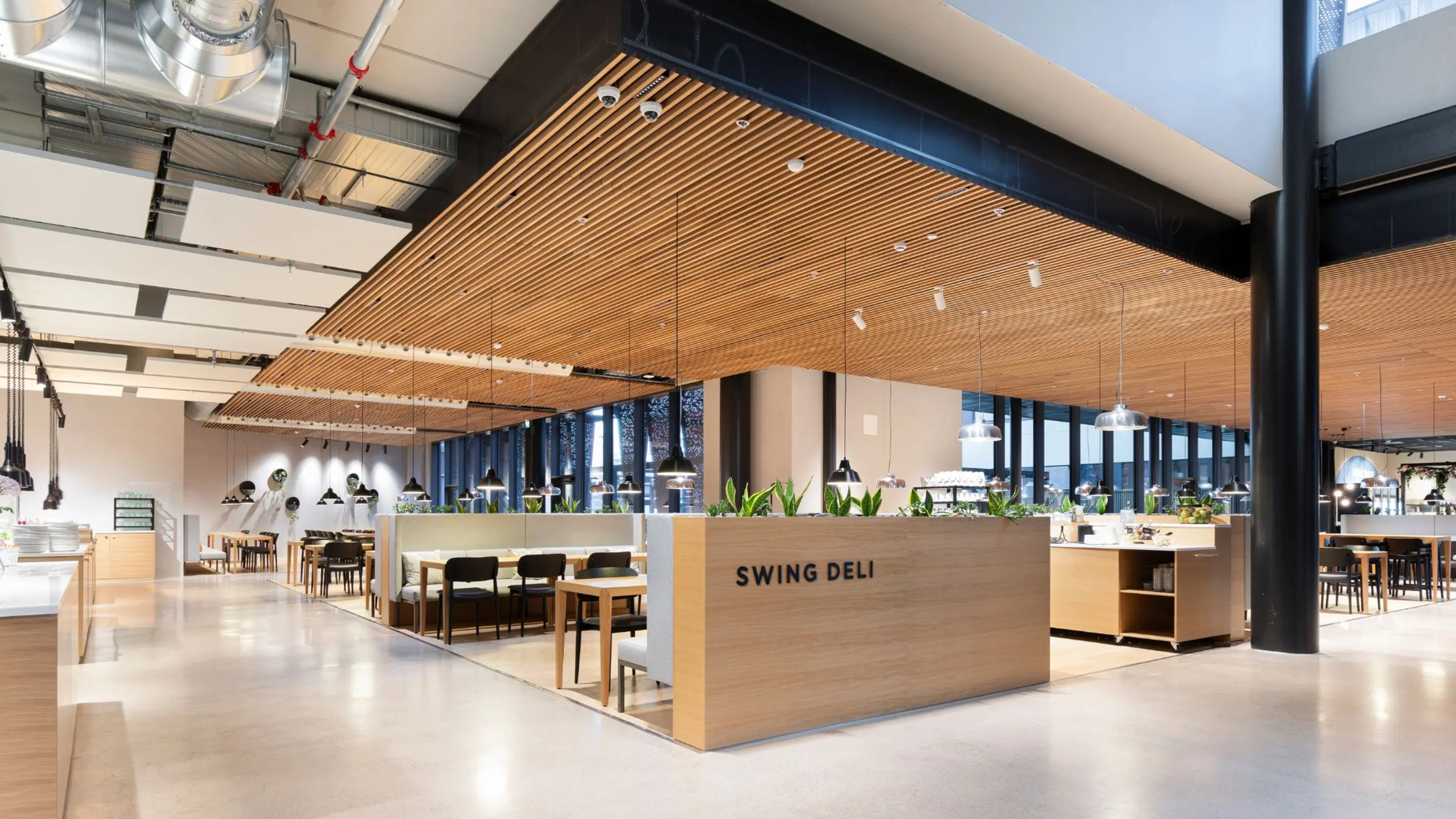 Modern restaurant interior with wooden ceiling panels, spacious area with flat floor and abundant natural light. Plants in wooden dividers.