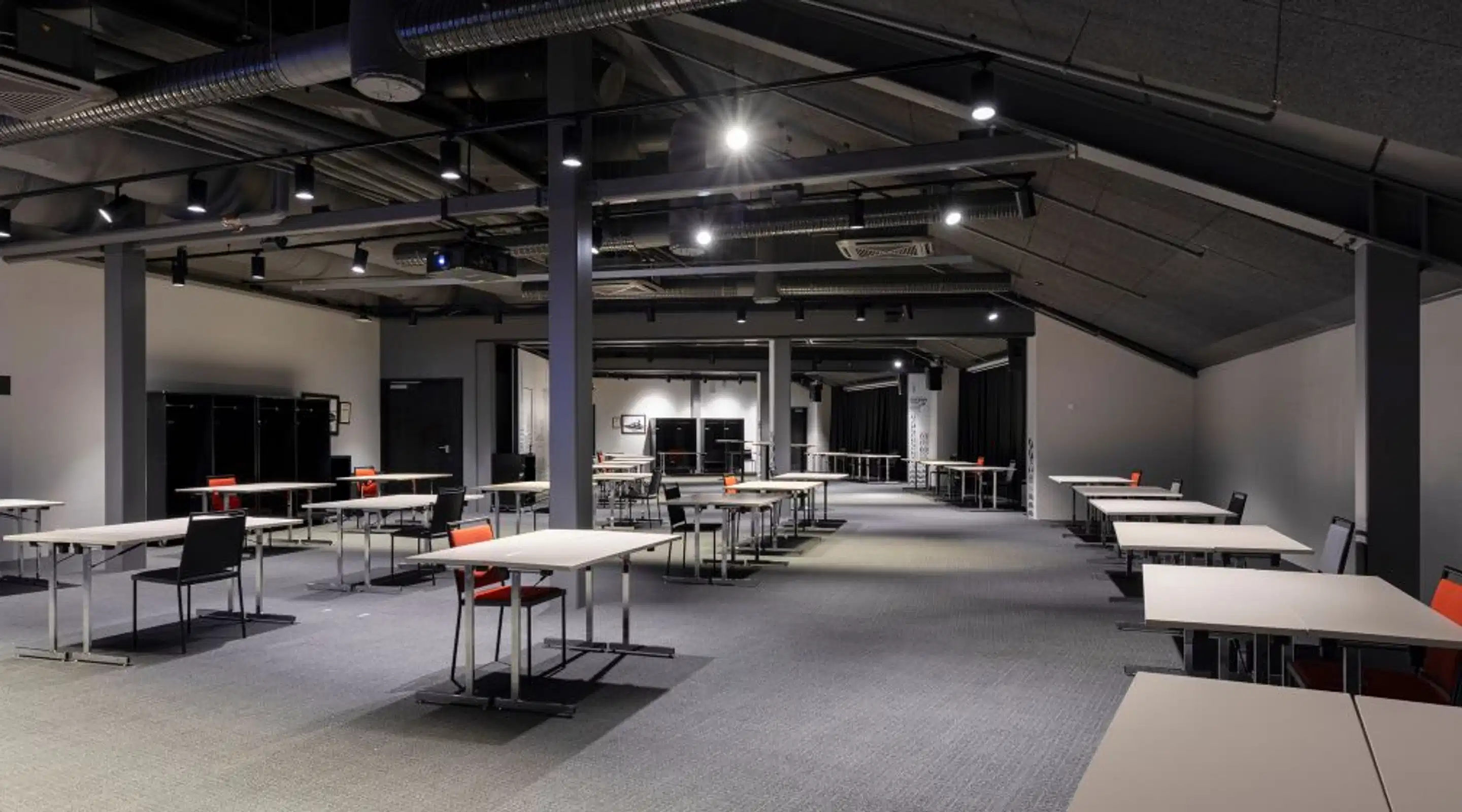 Spacious conference and event hall with level flooring, wide walkways, and industrial-style ceiling with exposed ductwork and lighting.