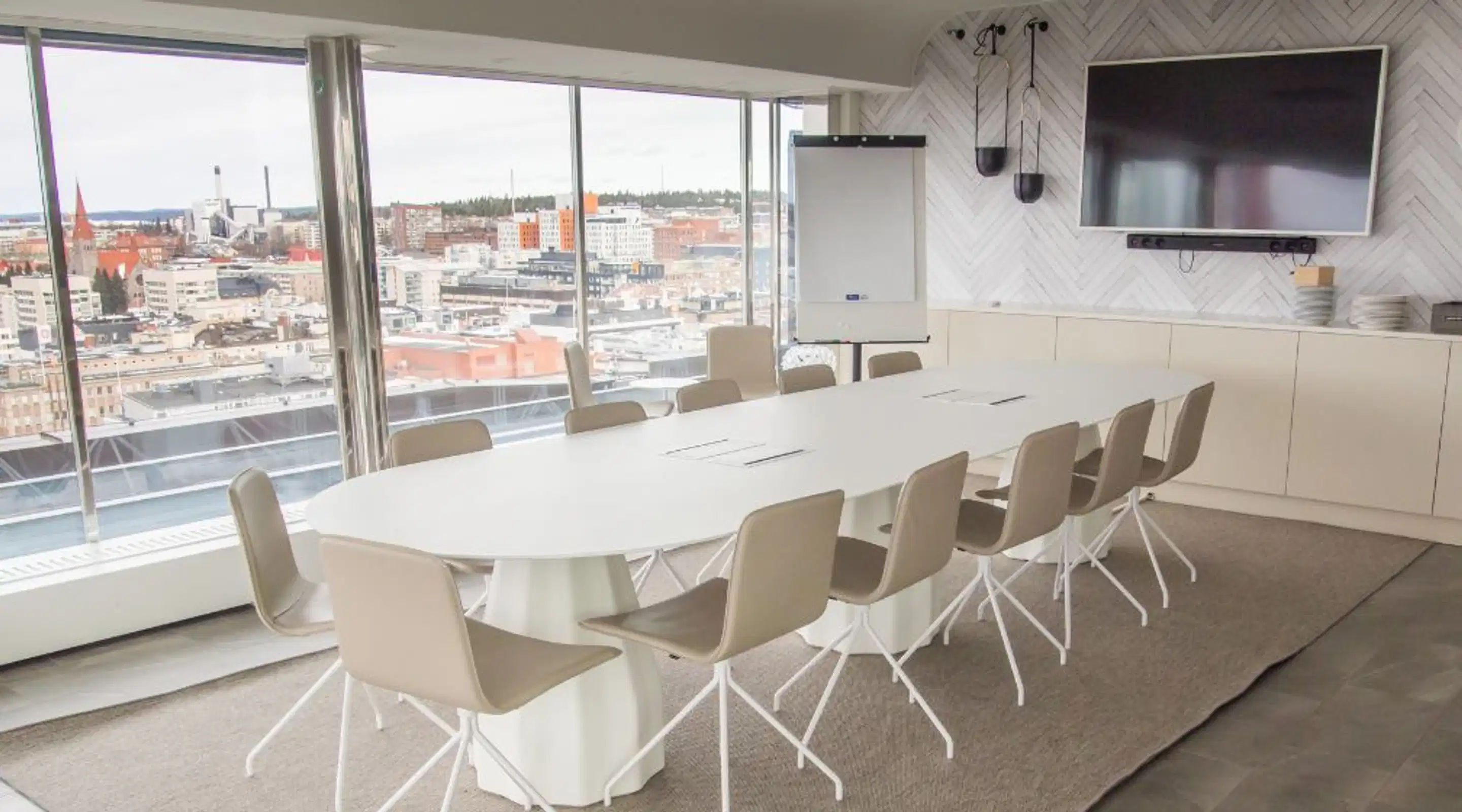Meeting room with white table and chairs, large window with city view and flat carpet as flooring material.