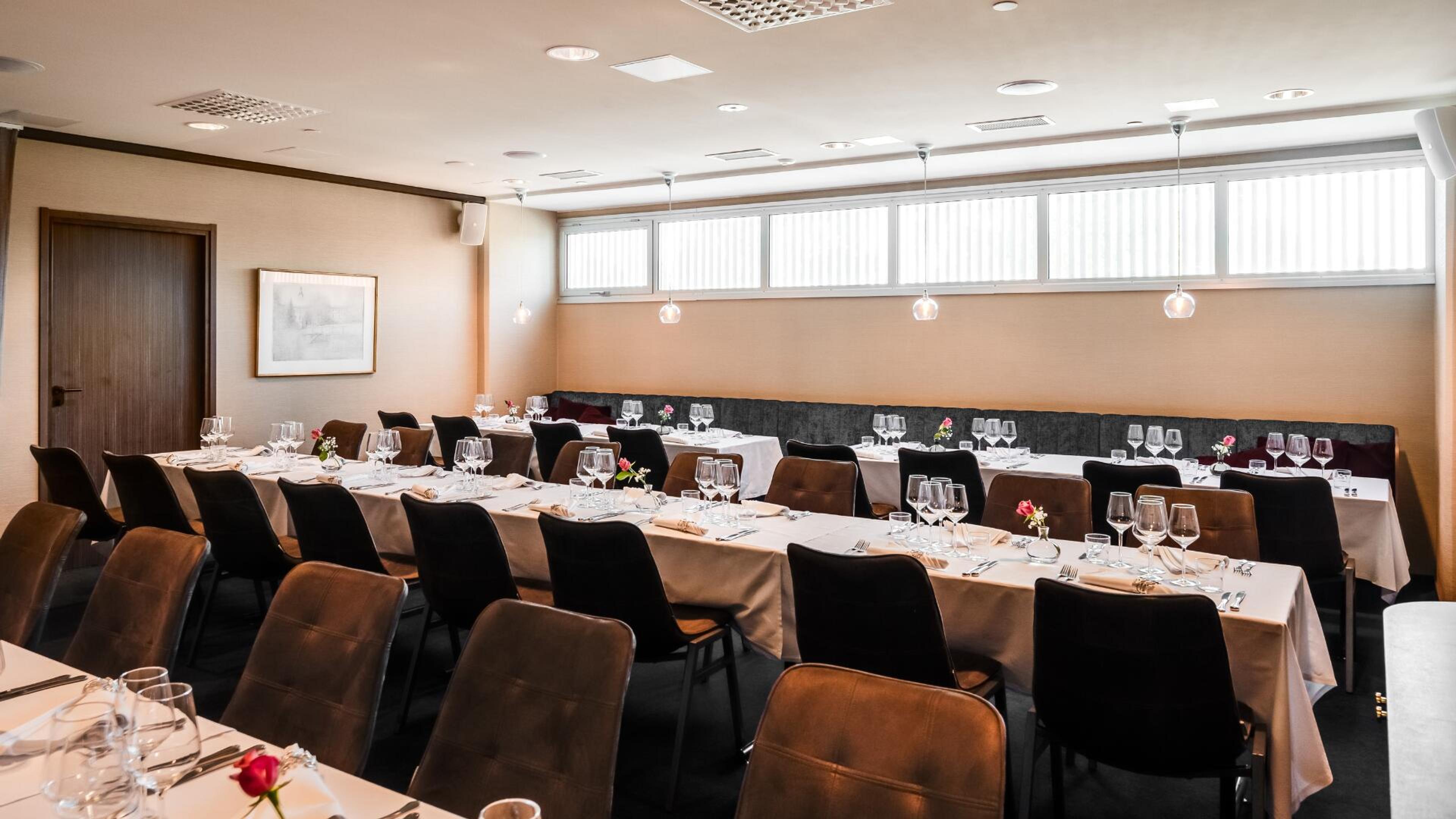 Ravintolan kabinetti, jossa pöydät on katettu juhlallisesti. Tila on valoisa korkeilla ikkunoilla.