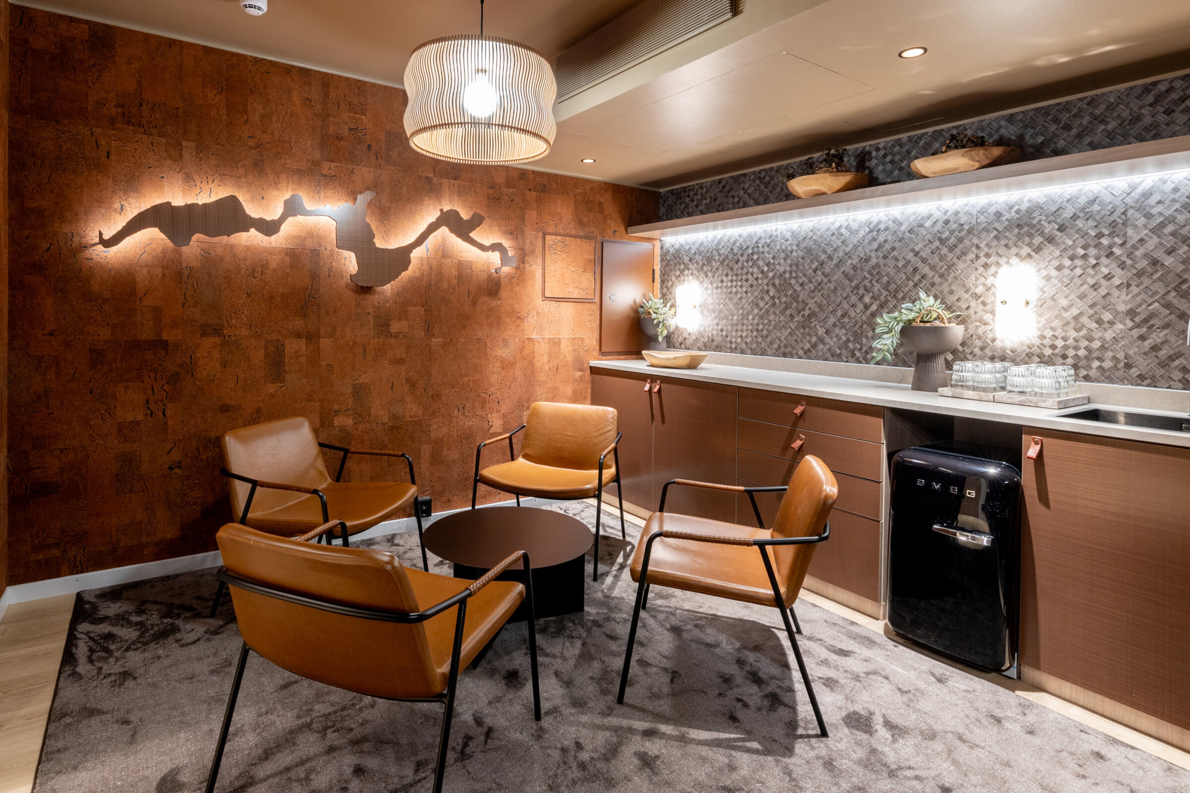 Lounge area with four leather chairs around a round table on a thick rug.