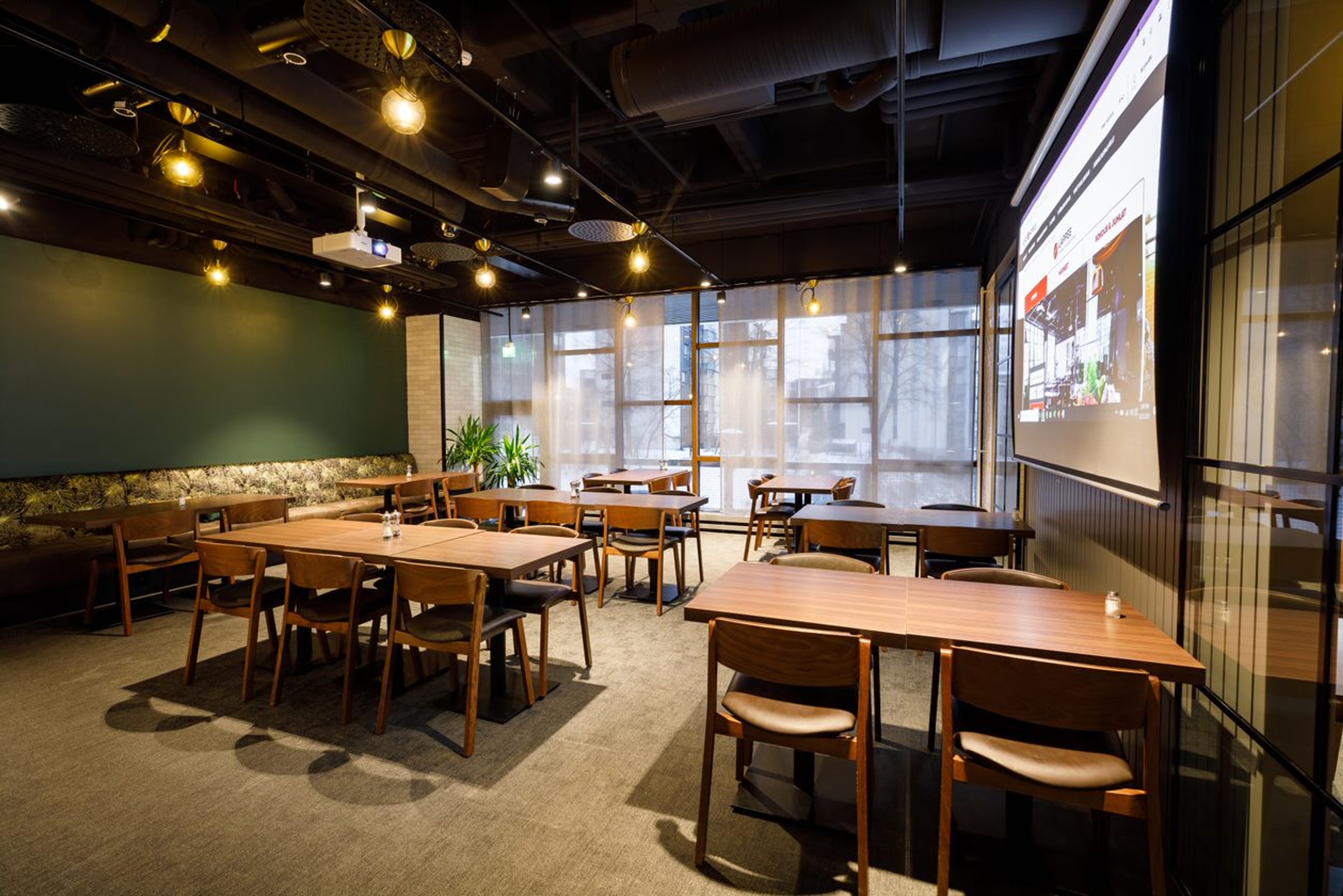 Moderni juhlatila, isot ikkunat ja projektorinäyttö