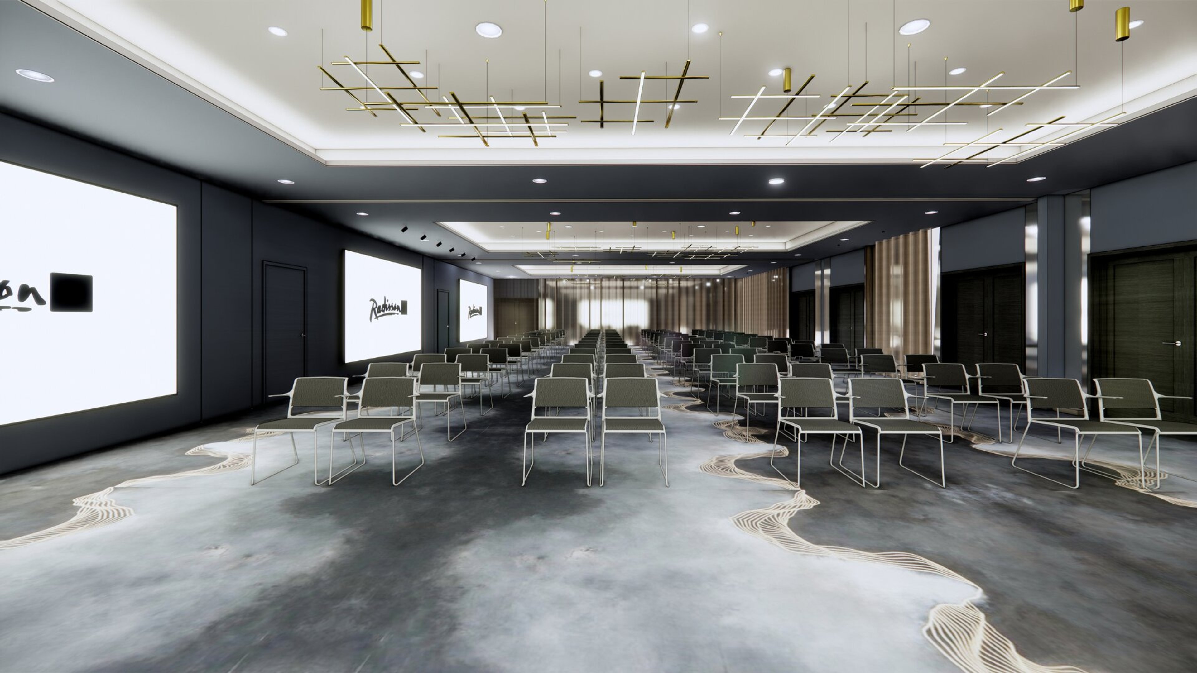 Moderni auditorio riveittäin järjestetyillä harmaa-valkoisilla tuoleilla, betonilattia ja tyylikkäät riippuvalaisimet katossa. Tummat seinät ja projektorinäytöt.