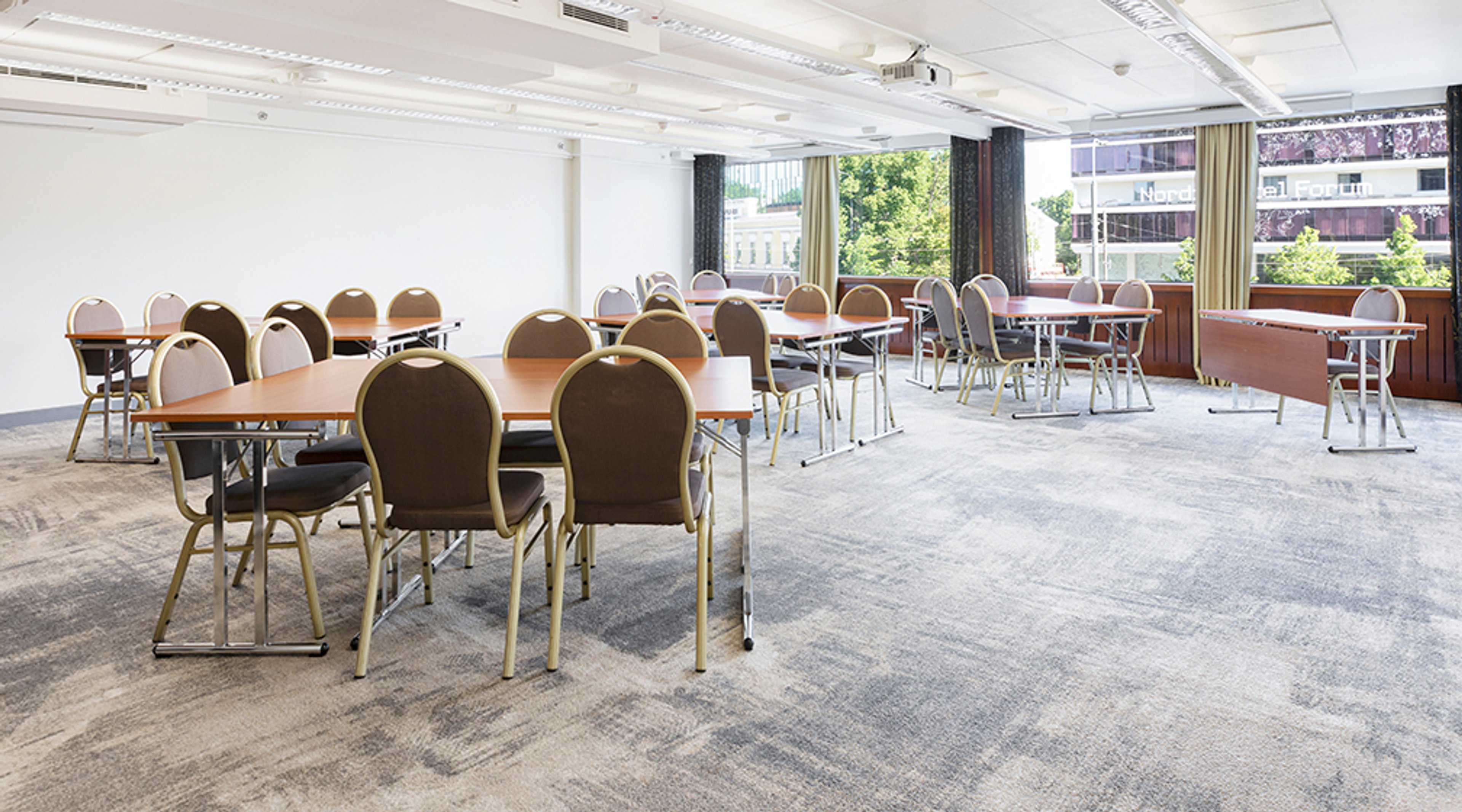 Conference room with multiple tables and chairs, short-pile carpet, and large windows.
