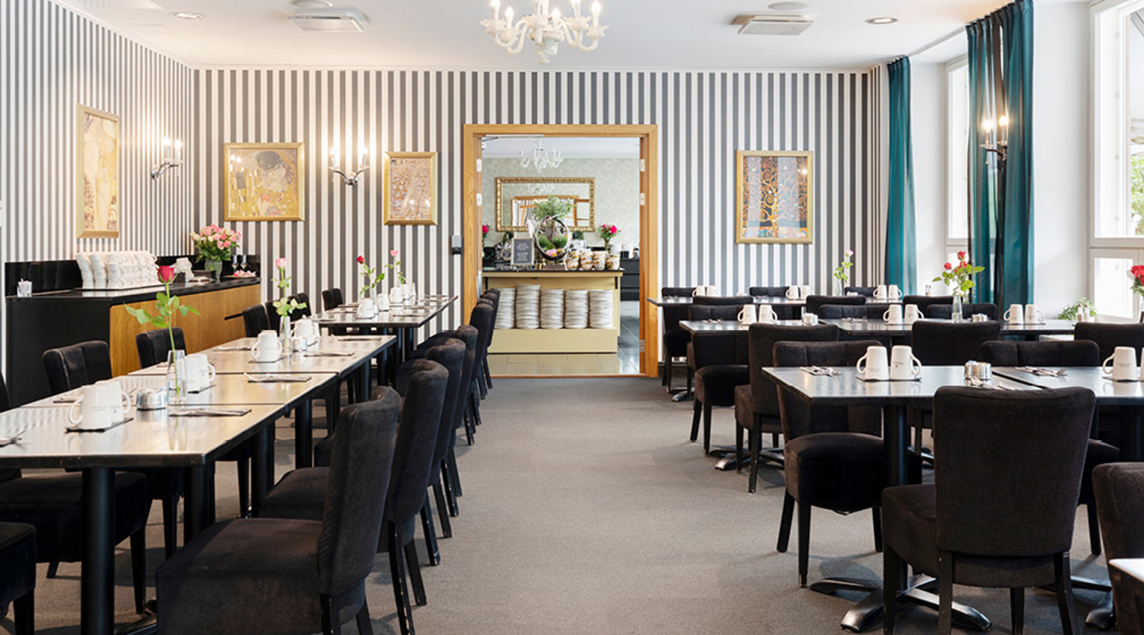 Restaurangsal med randiga väggar, mörka bord och stolar, kortslitaget mattor.