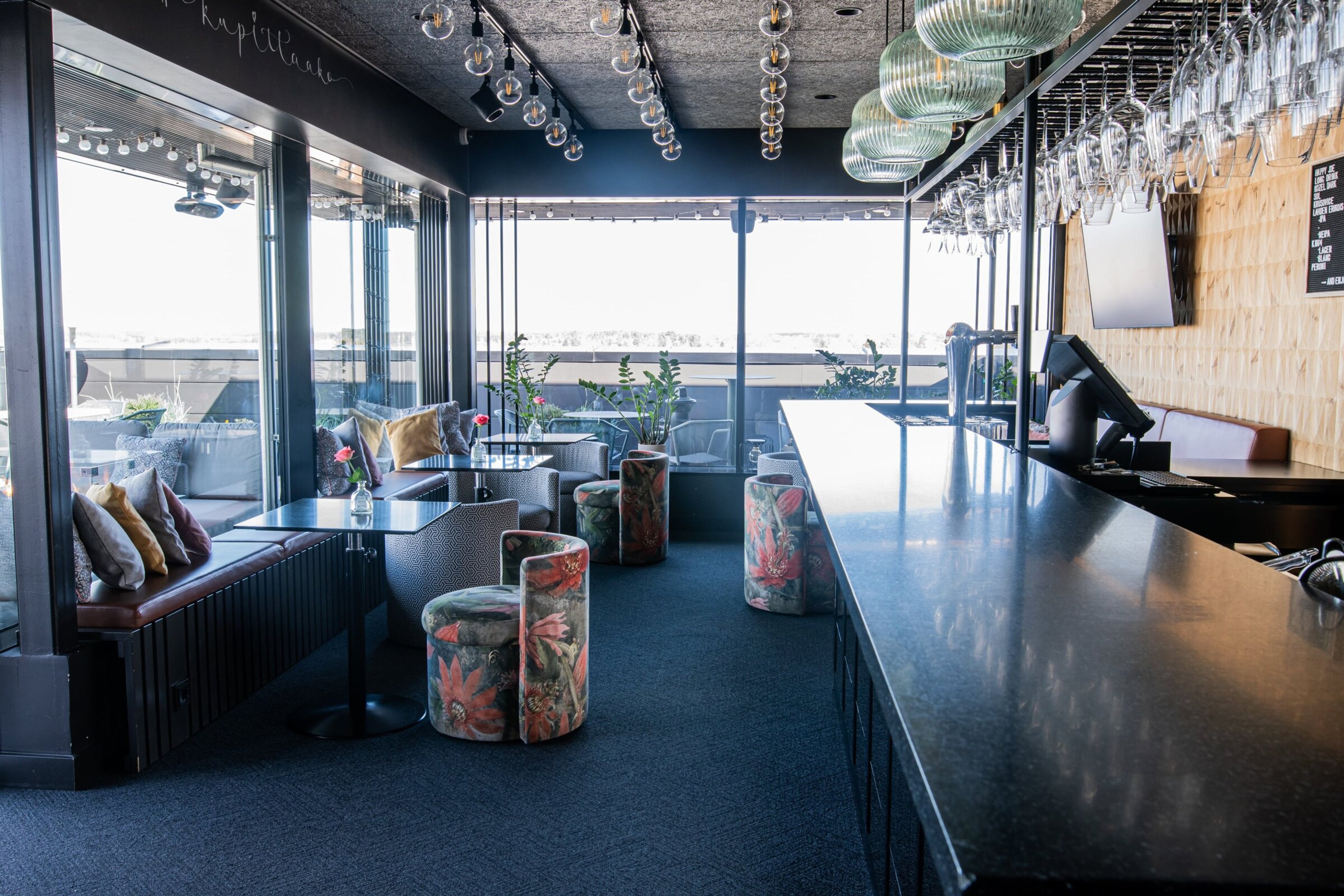 Kuppis Rooftop Bar sisätila, jossa pitkä baaritiski, istumapaikkoja ja näkymä terassille.