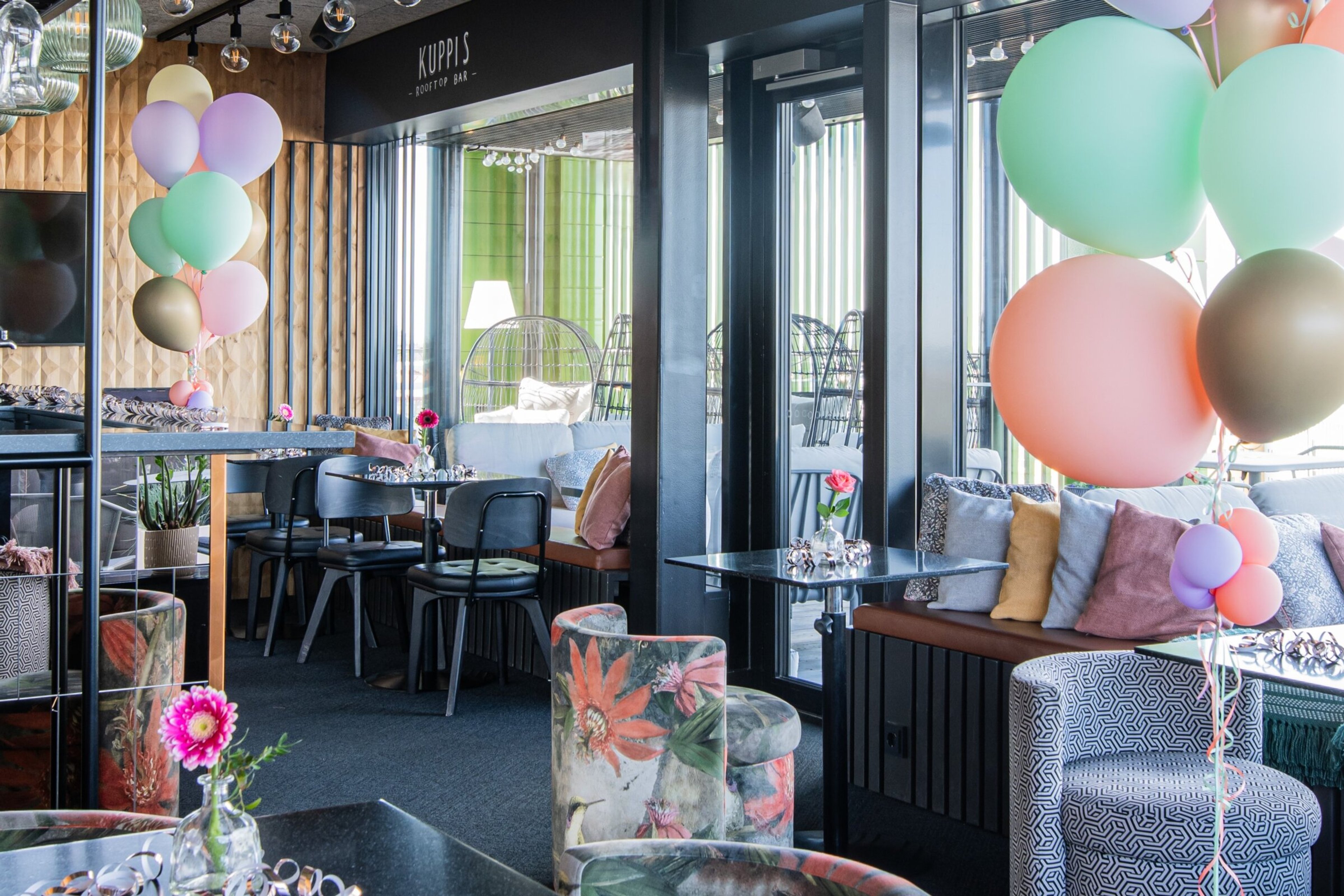 Kuppis Rooftop Bar, jossa koristeena värikkäitä ilmapalloja, erilaisia istumapaikkoja ja pieniä ruokailupöytiä.