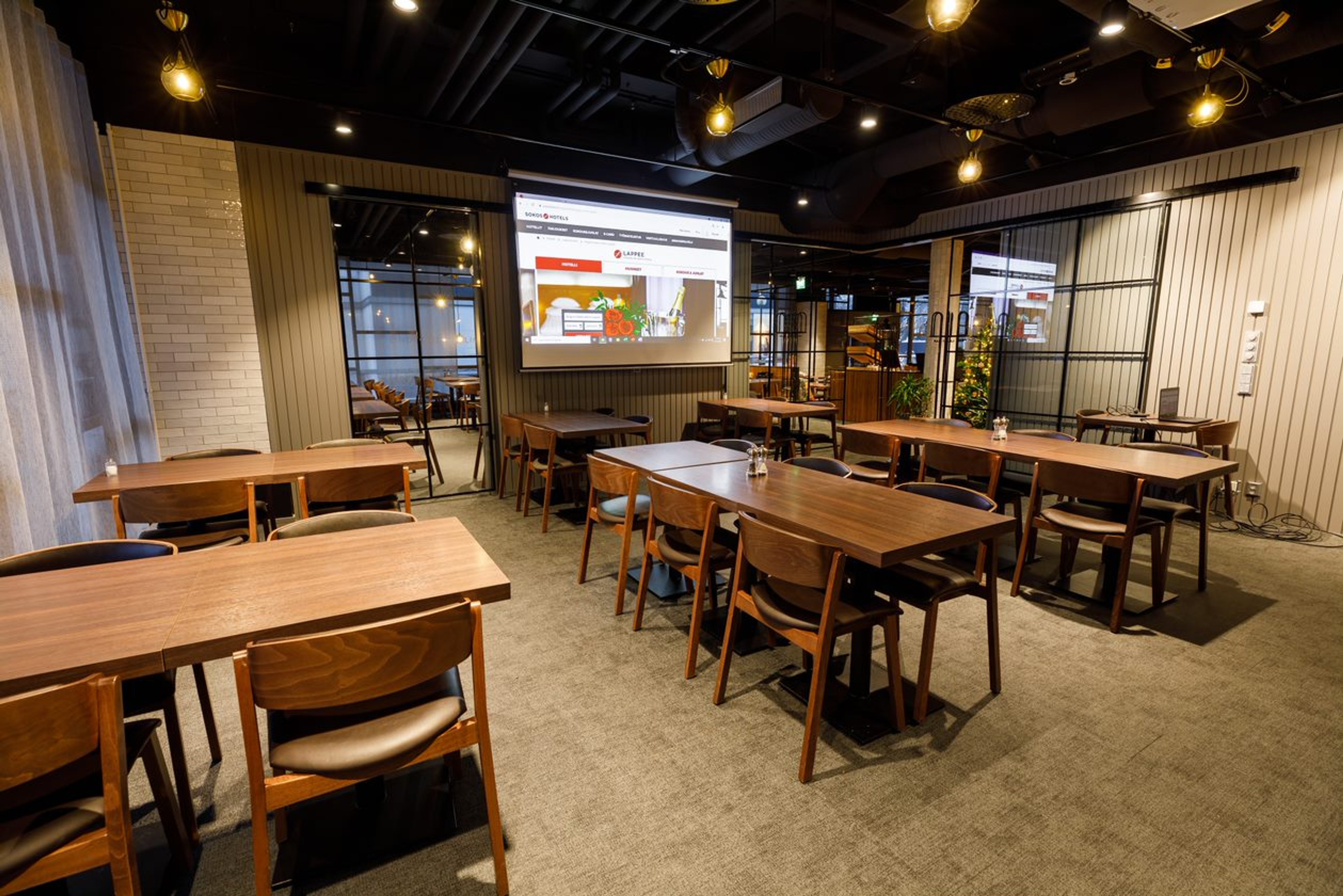 Kokoustila ja juhlatila, jonka seinällä esitysnäyttö.