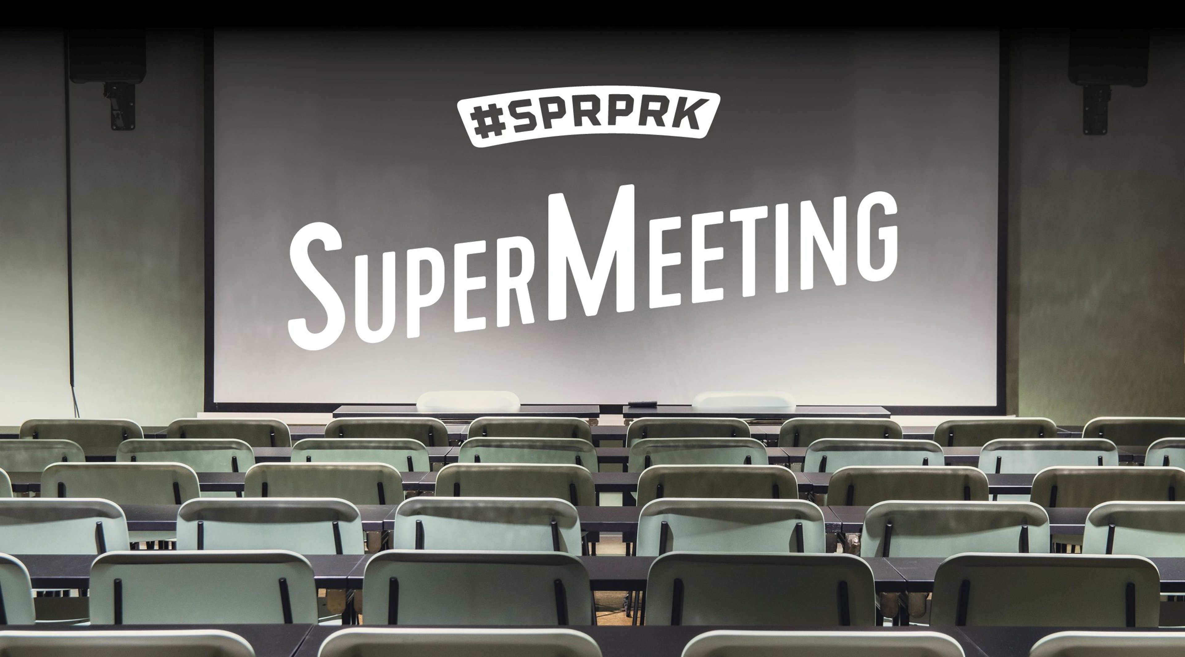 Tyhjä kokoustila, jossa on vaaleita tuoleja riveittäin ja edessä suuri valkokangas.