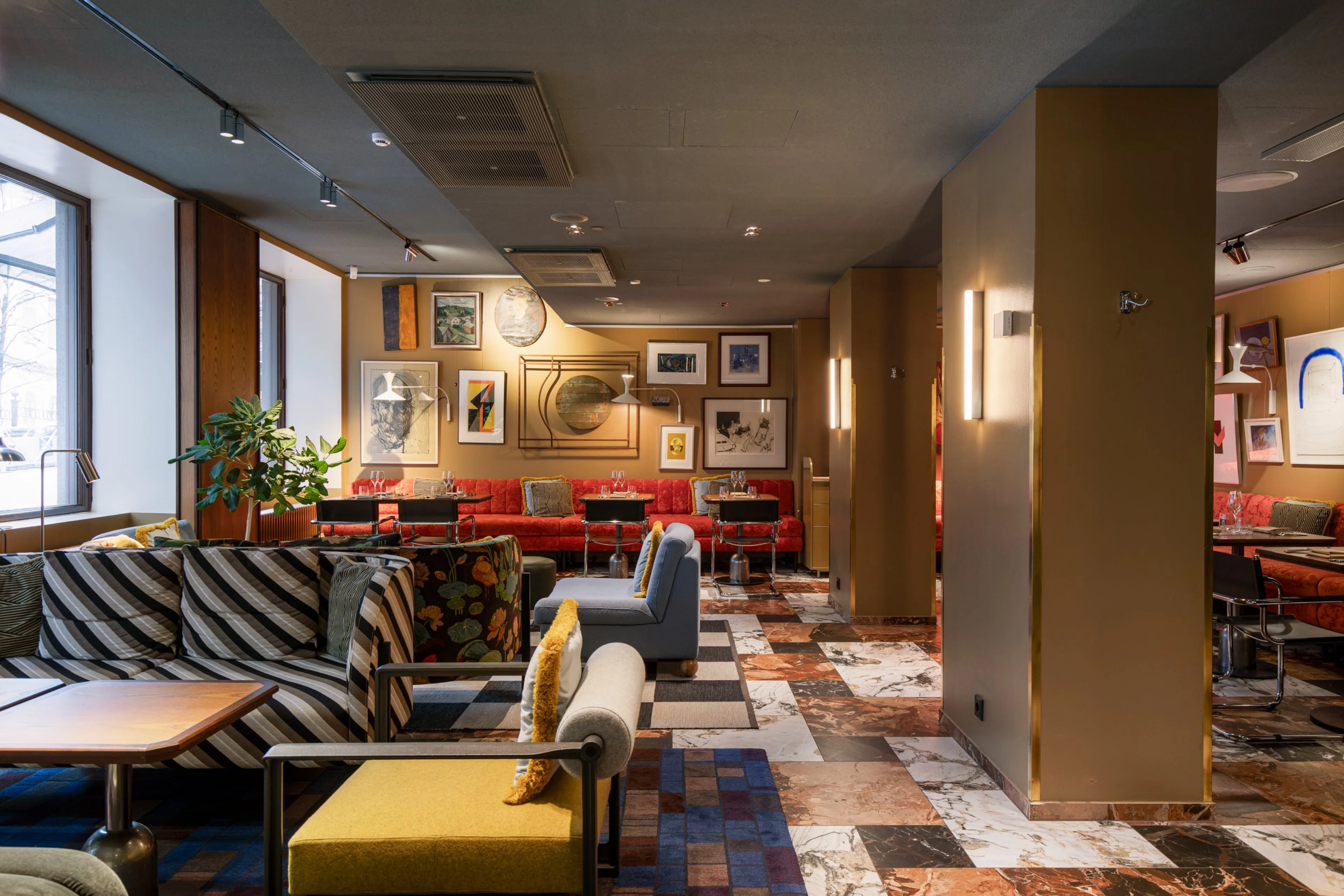 Värikkäästi sisustettu ravintola, jossa punaiset sohvat, taideteoksia seinillä ja marmorilattialla erilaisia mukavia istuinryhmiä. Runsaasti luonnonvaloa ikkunoista.