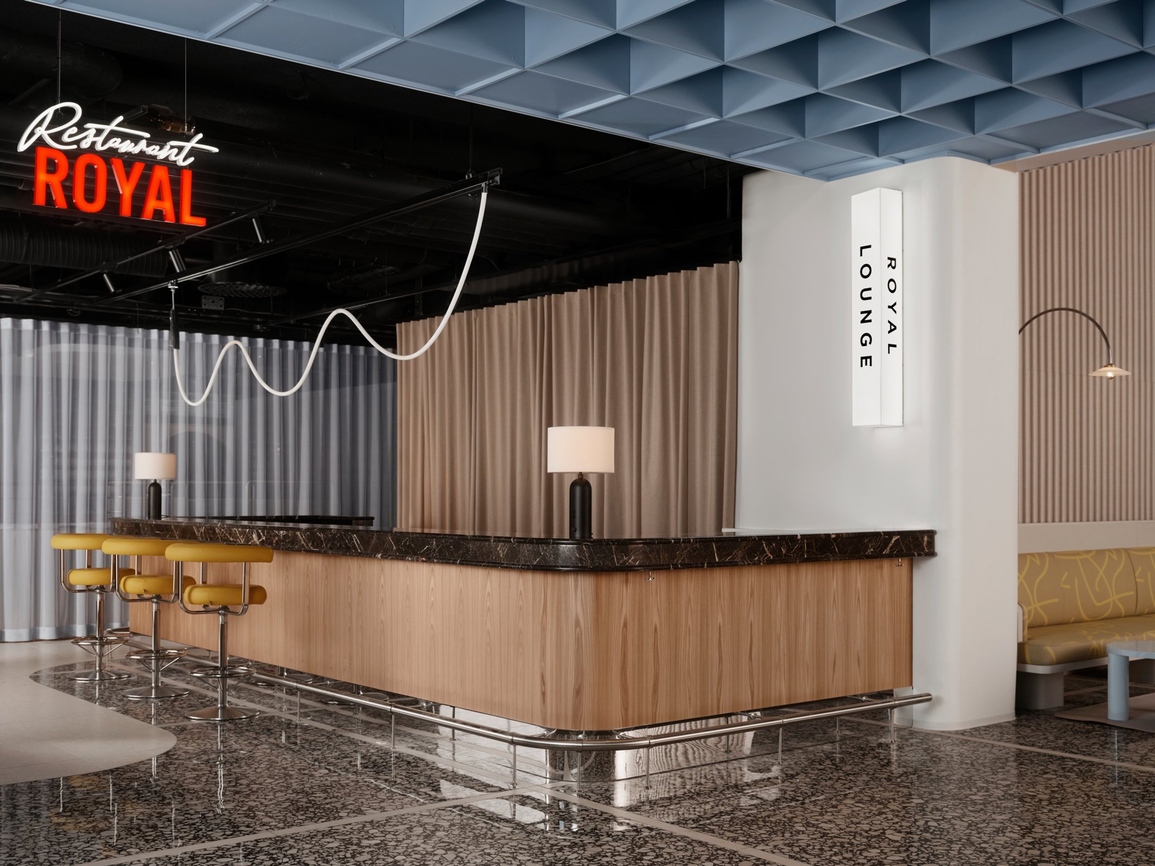 Royal-ravintolan moderni baaritiski marmoripinnalla, keltaisilla baarituoleilla ja tyylikkäällä sisustuksella. Lattia on tasainen graniitti.