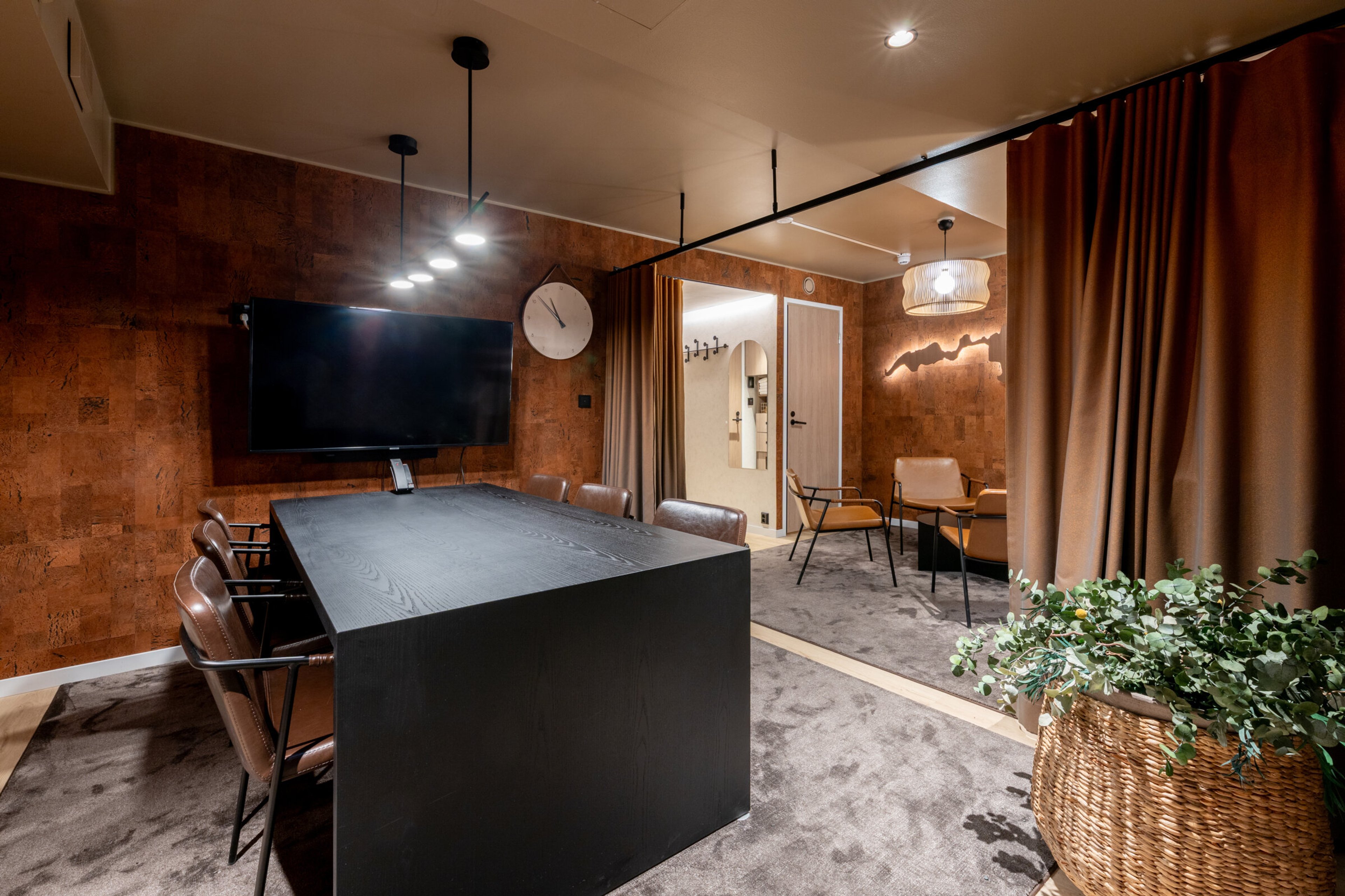 Meeting room with dark table, leather chairs, cork walls and soft carpet flooring.