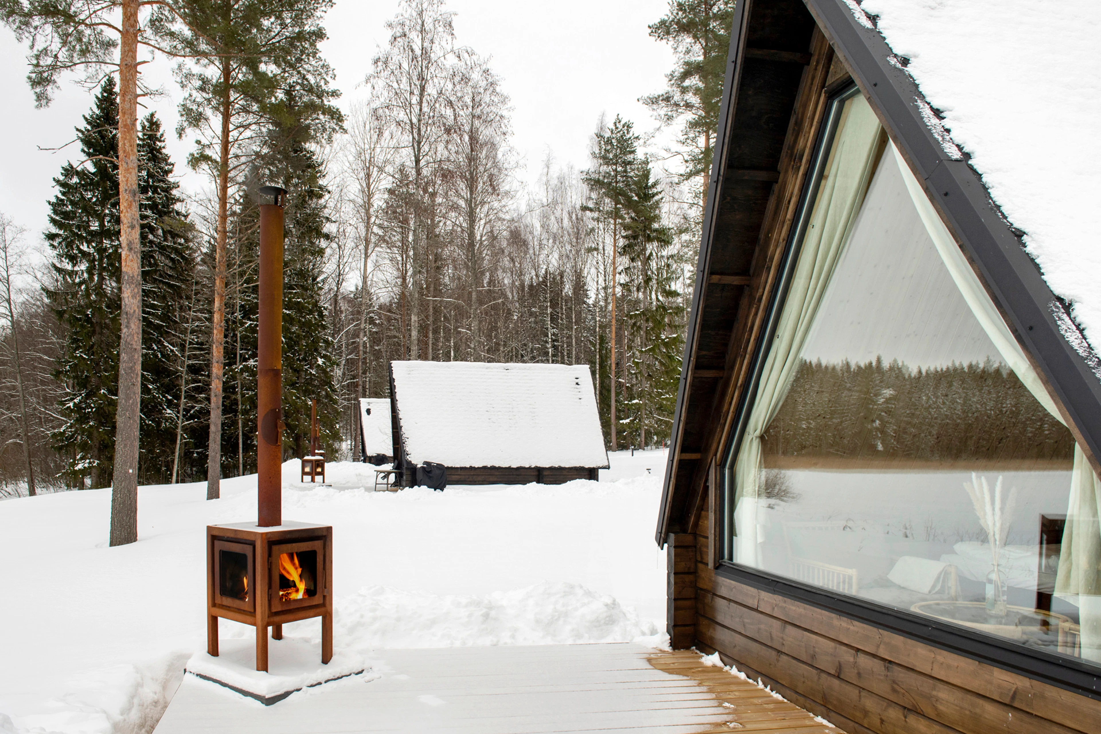 Laawu talvimaisemassa. Pieni ulkotakka palaa puisella terassilla.