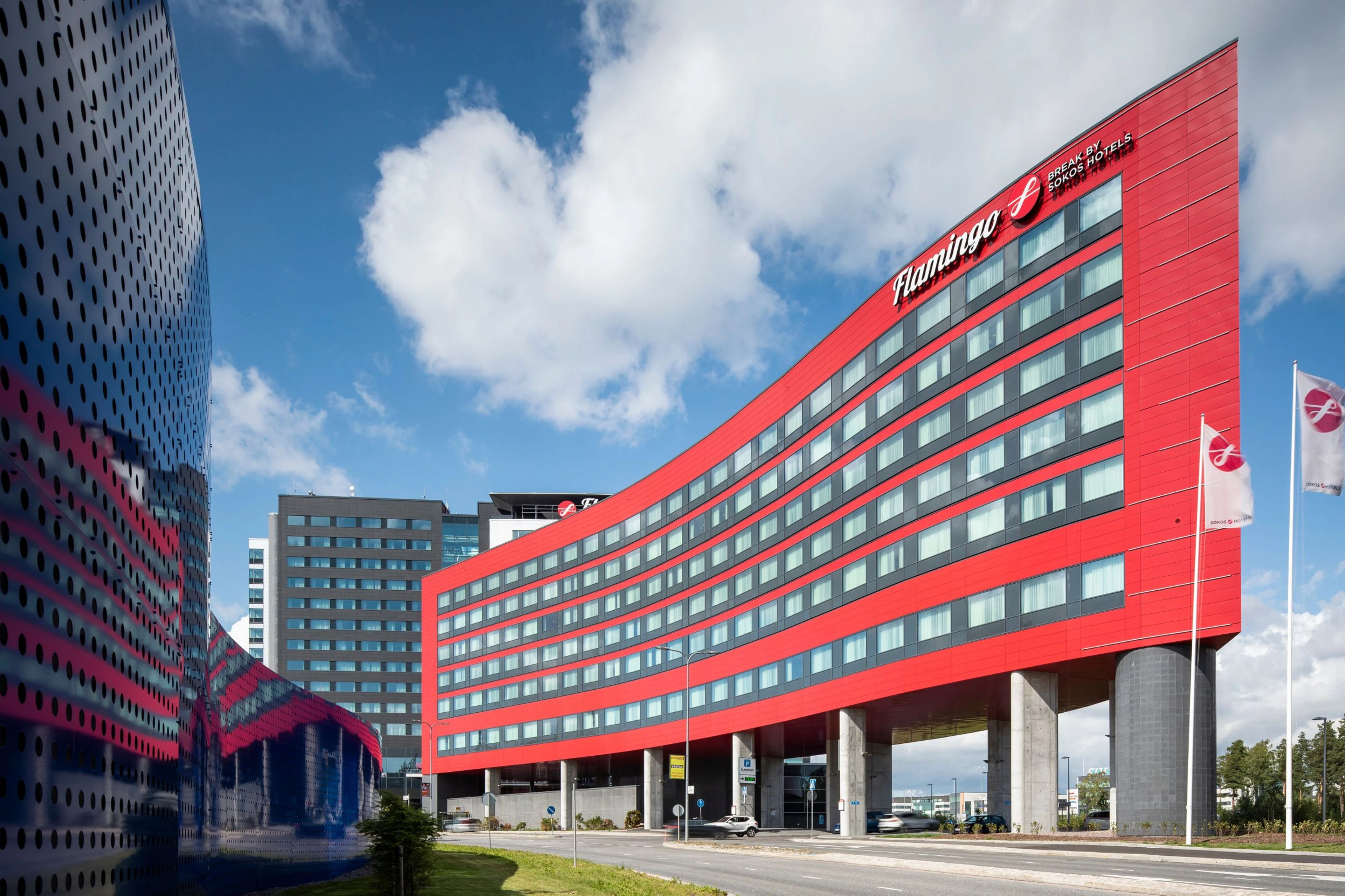 A red building with a lot of windows that has in the top right corner the Sokos Hotel Flamingo logo