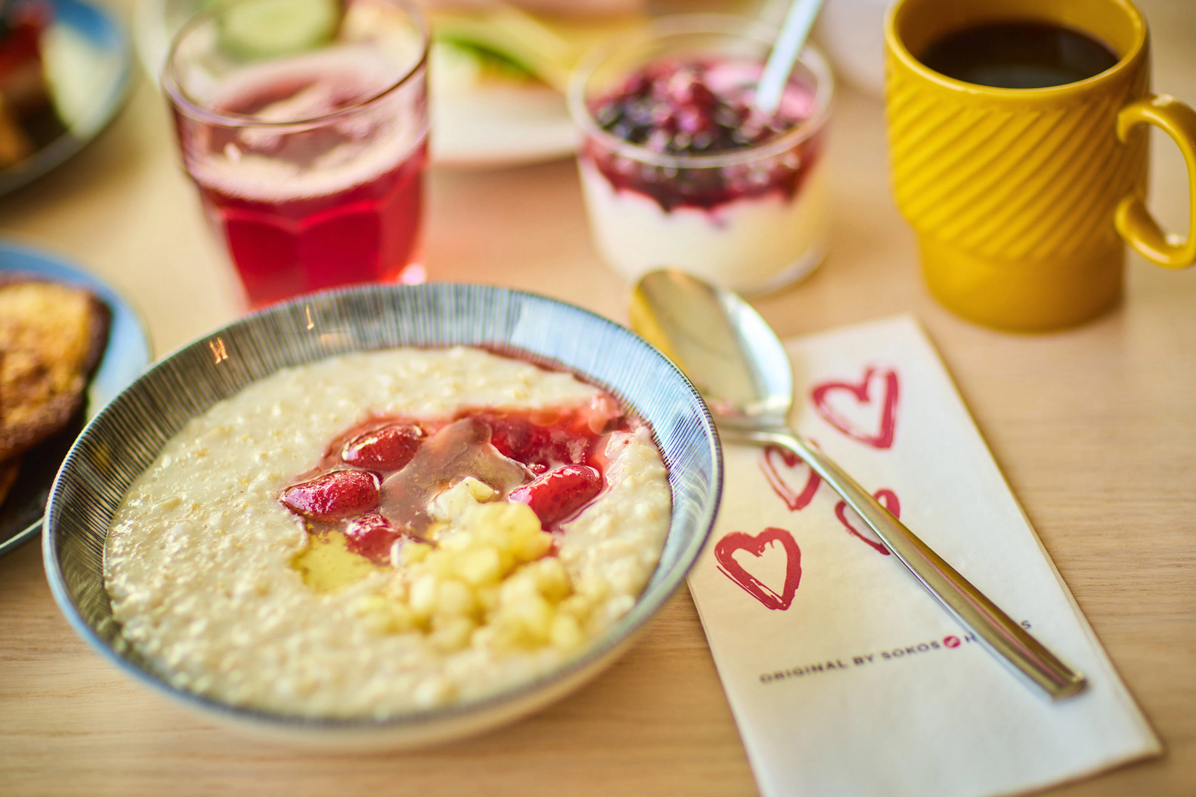 Hotellin aamiaispöytä, jossa puurolautanen, jugurttiannos, juomalasi ja muki.