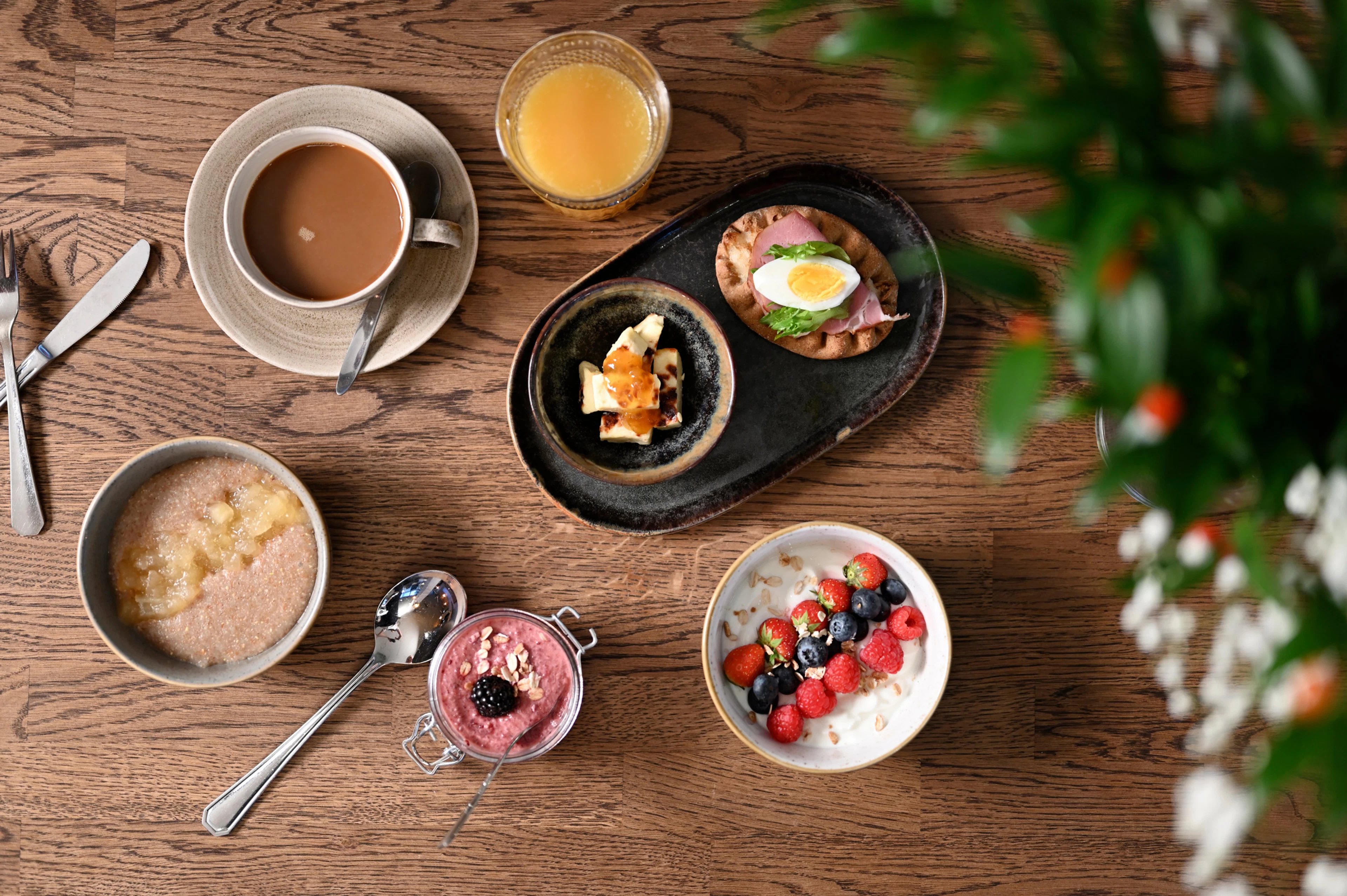 En fräsch och läcker hotellfrukost uppdukad på bordet, innehållande gröt, yoghurt, juice och kaffe.