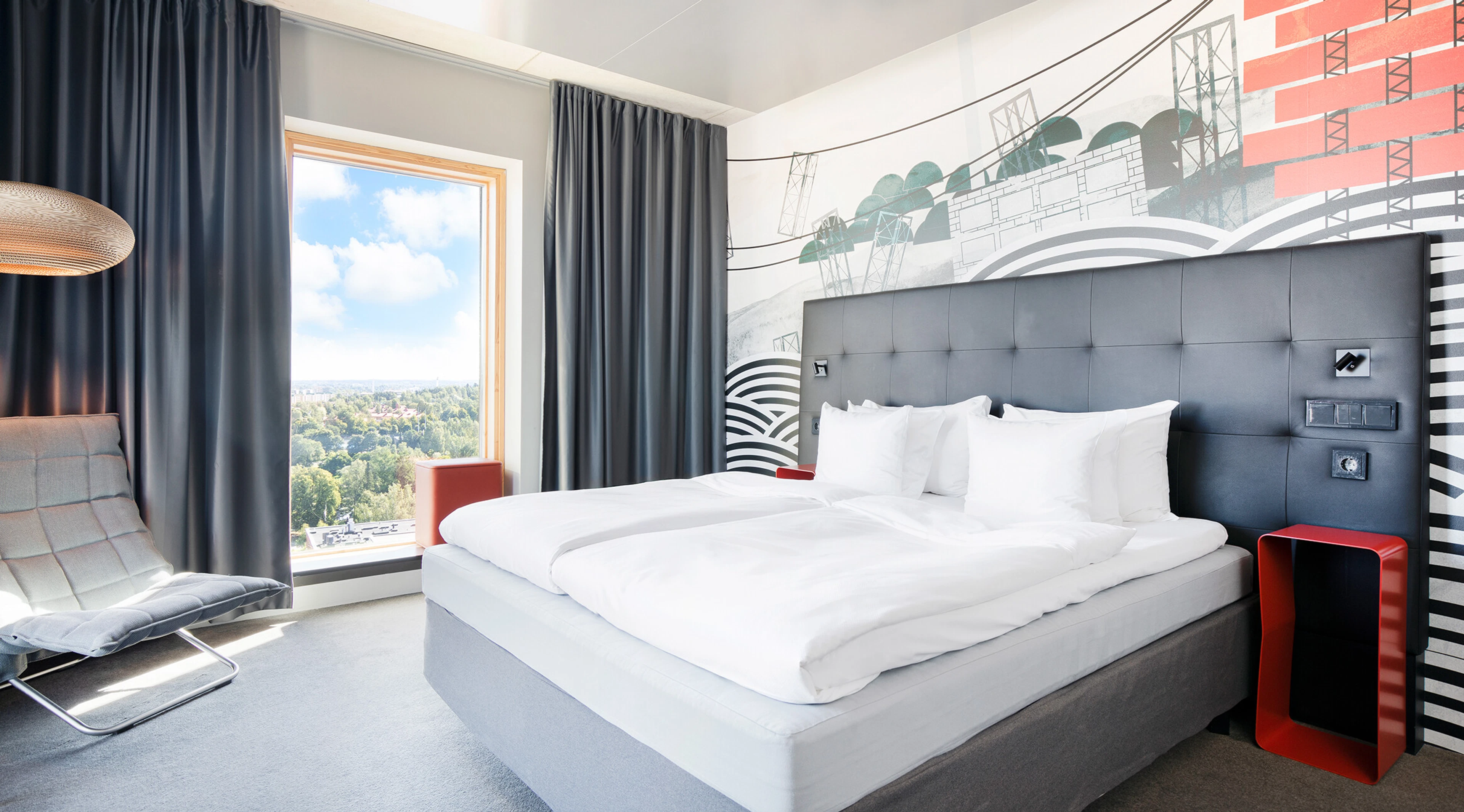 Modernt hotellrum med en stor säng, högt fönster och jämnt golv.