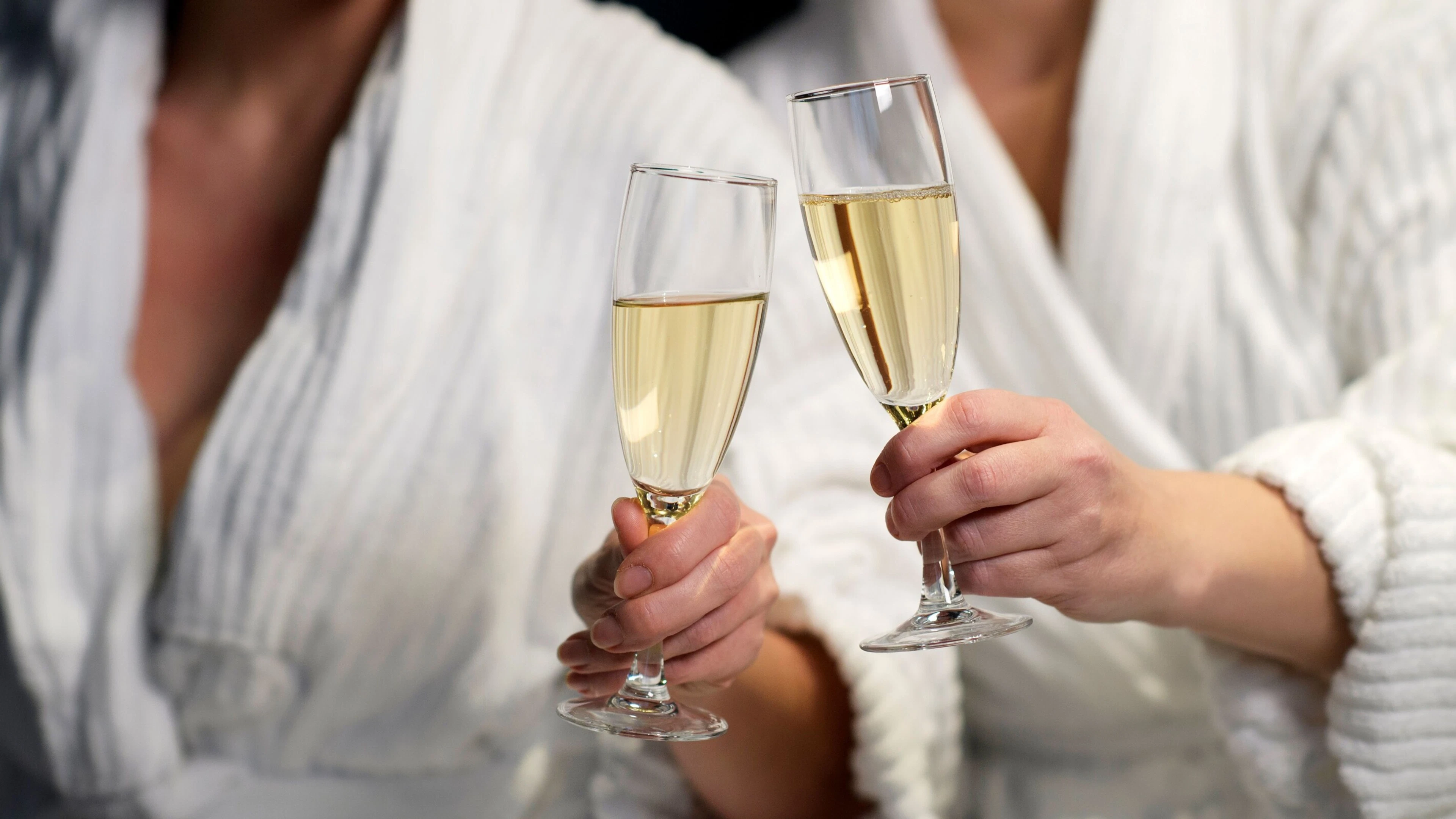 Två personer håller champagneglas och skålar.