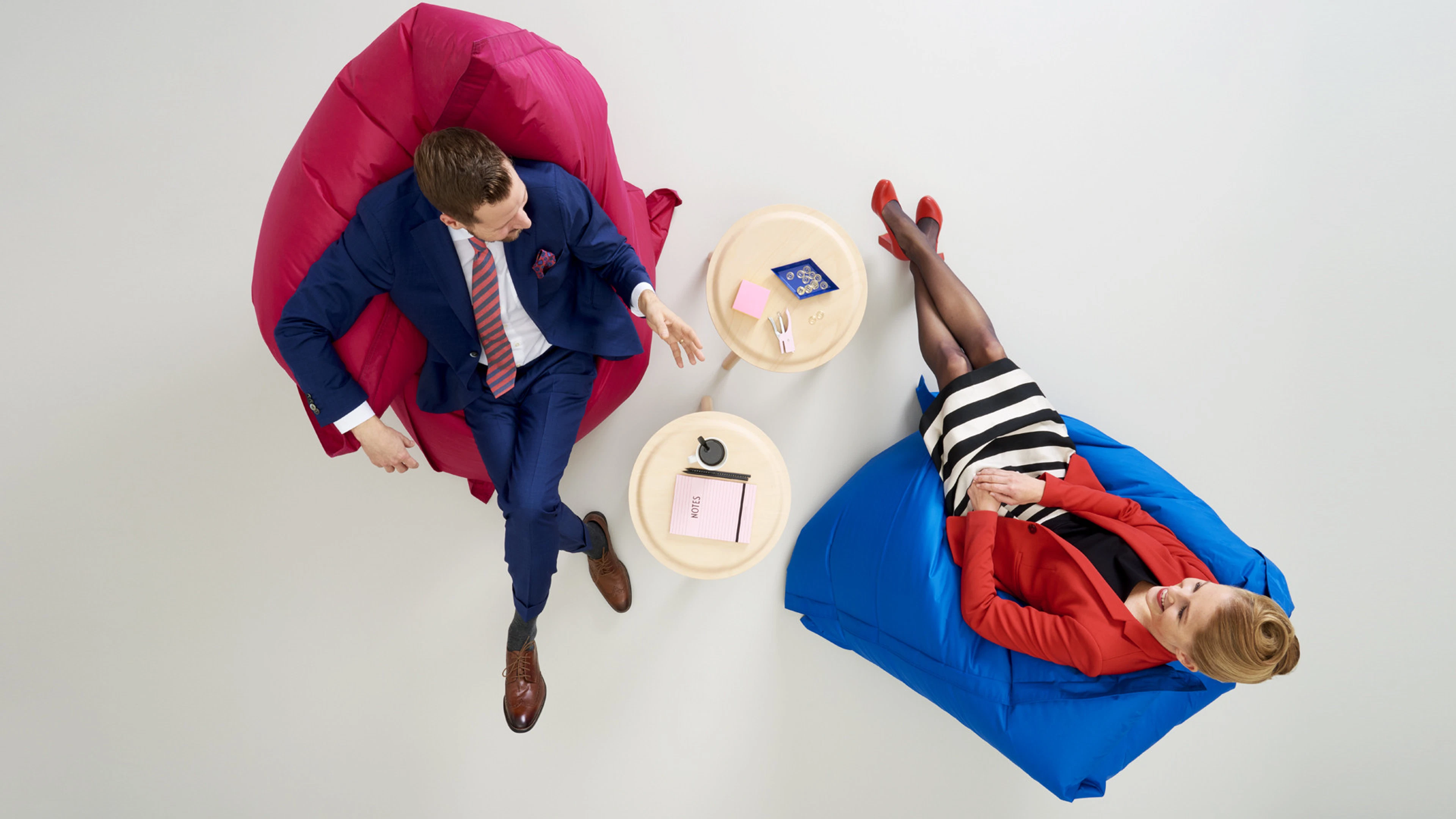 Overhead view of lounge seating area with two large bean bags and round side tables on hard floor.