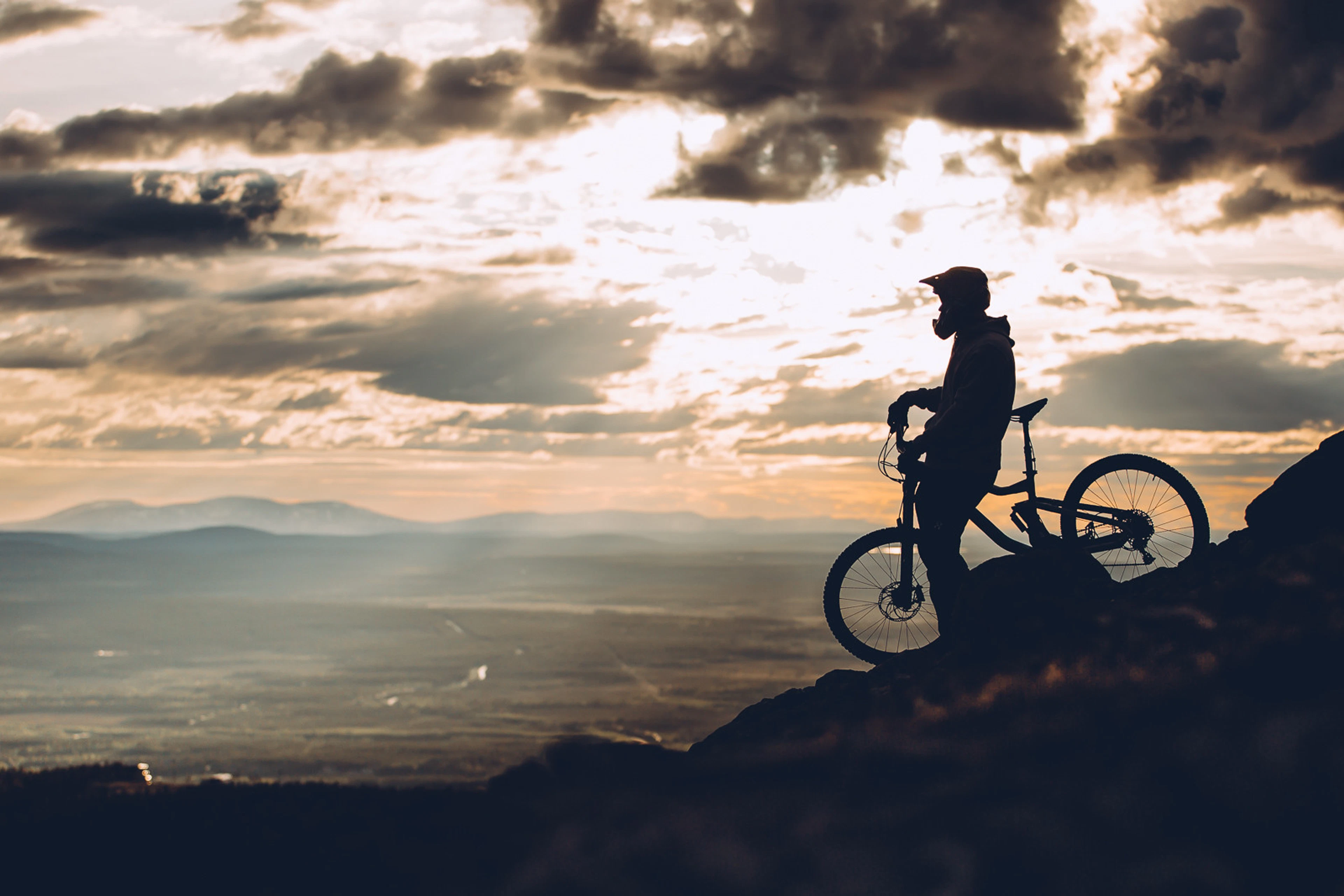 Cyclist with mountain bike on rocky outcrop at sunset. Rocky terrain.