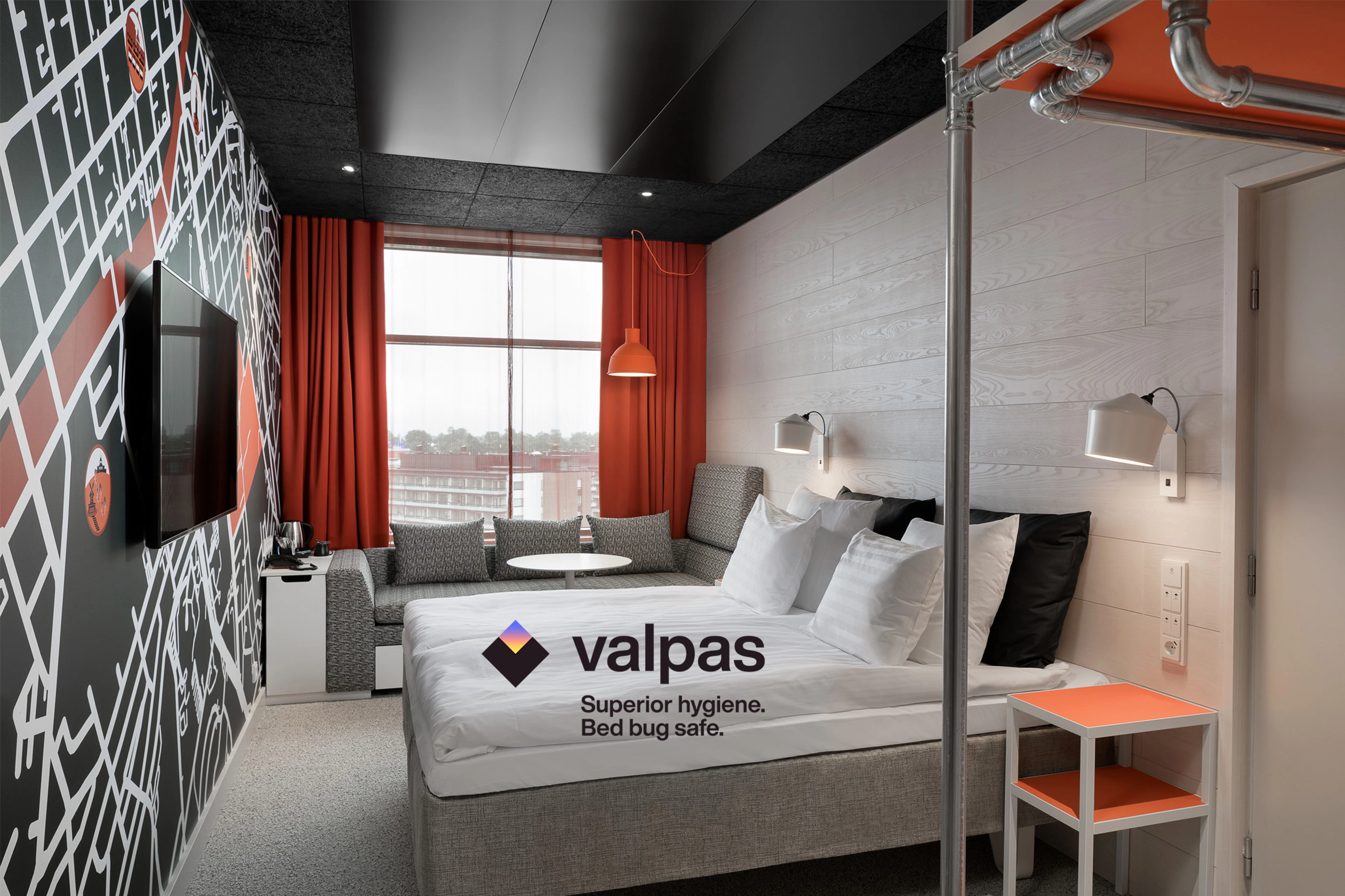 Original Sokos Hotel Kupittaan hotellihuone, jossa tehostevärinä oranssi. Kuvassa parivuode ja sohva.