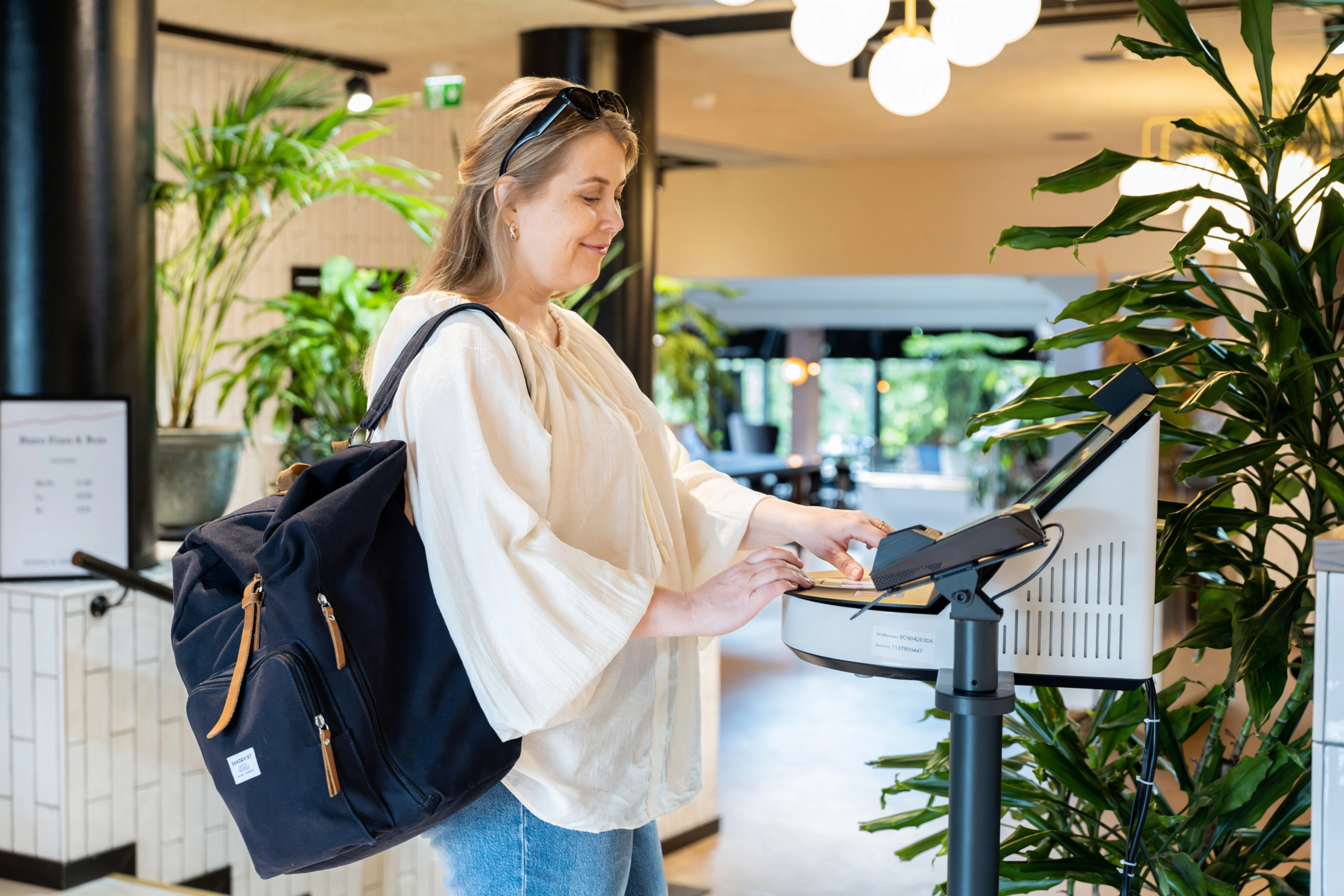 Woman dooing check.in to the hotel with self-service kiosk