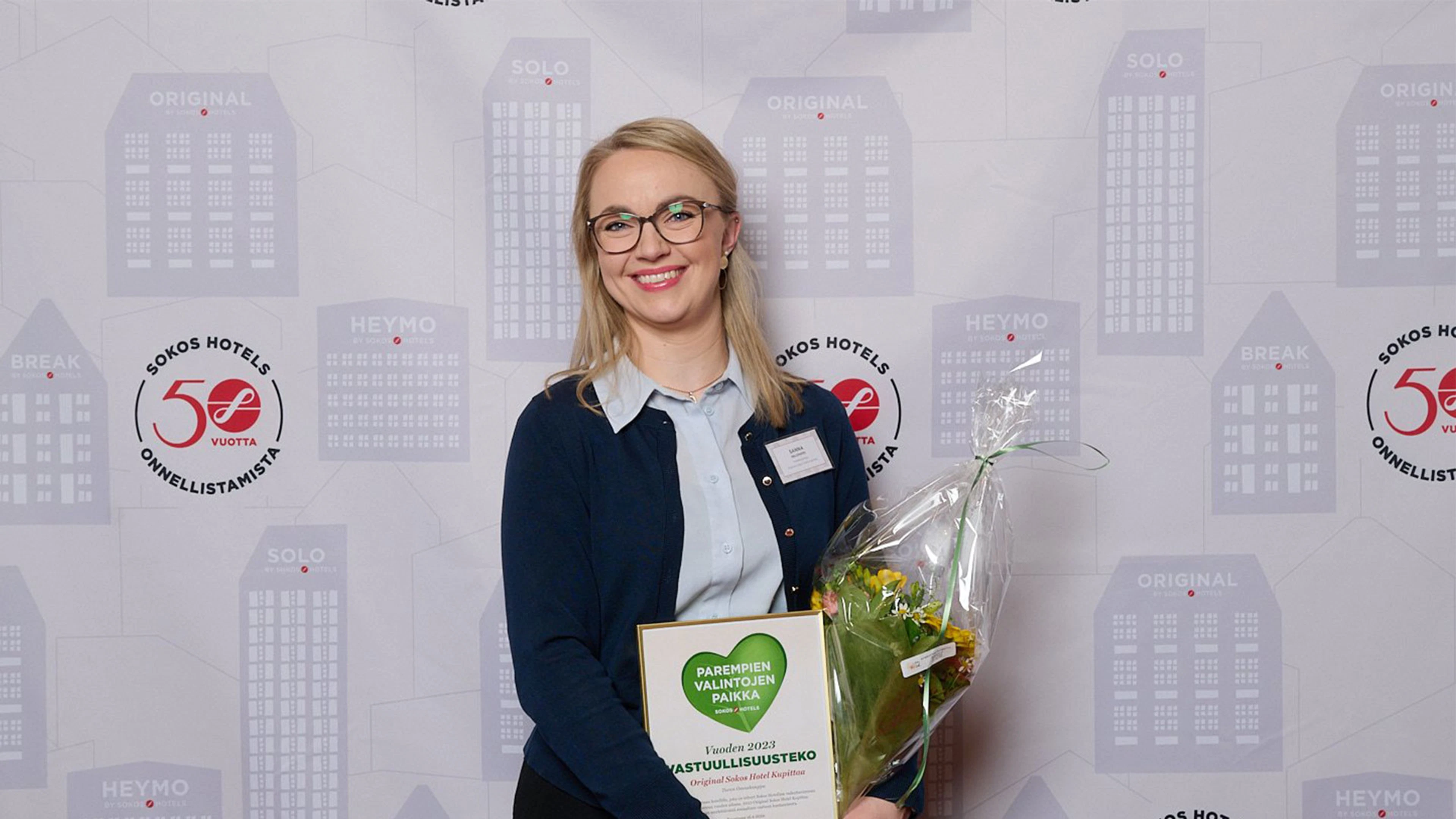 Hotel manager Sanna Paloniemi smiling at the Sokos Hotels awards gala with a trophy and flowers.