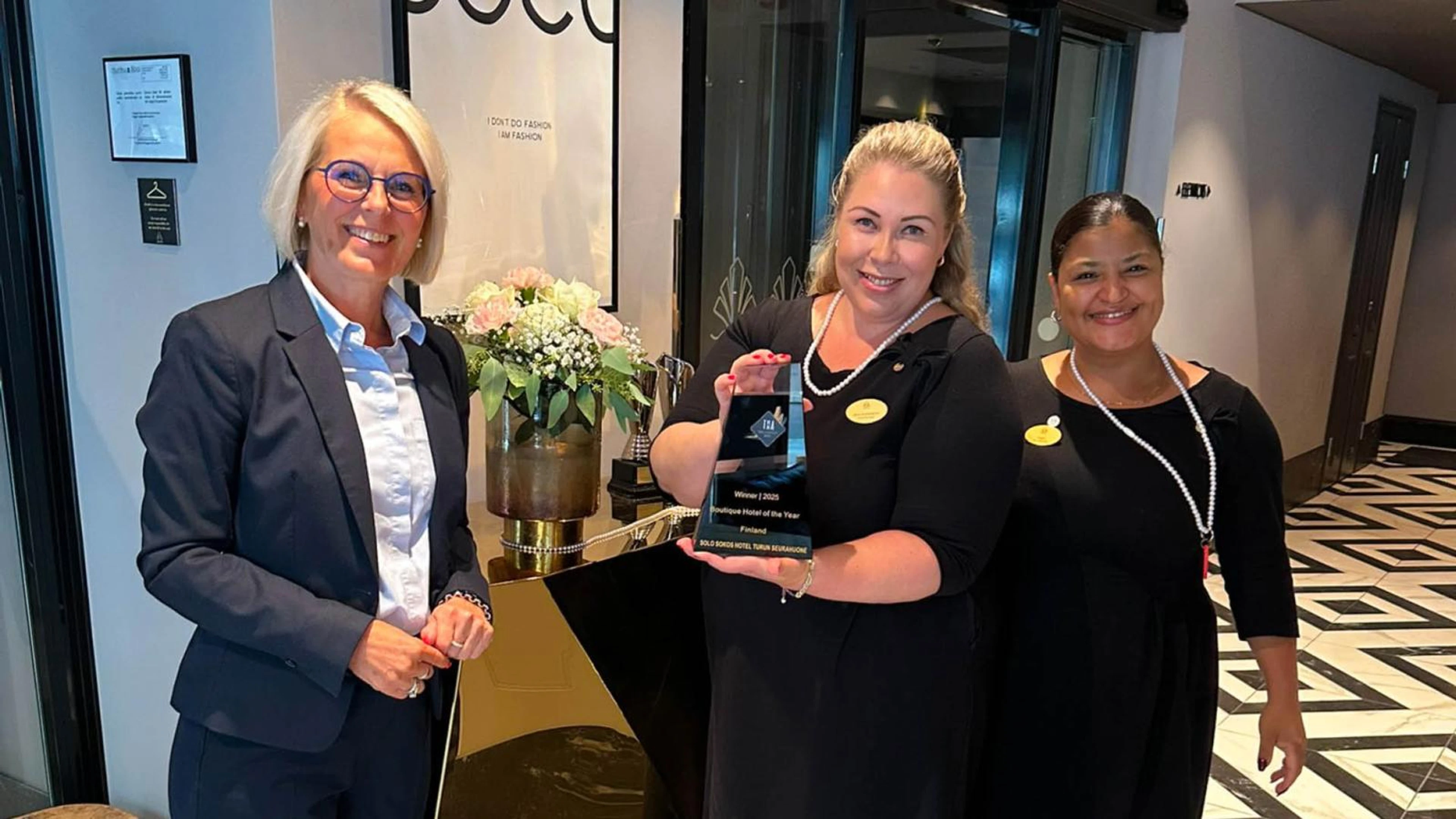 Hotellinjohtaja Tarja Jalone, vt. hotellipäällikkö Nina Kemppainen sekä vuoropäällikkö Helem Halonen hotelliaulassa iloisina esittelemässä kansainvälistä Travel & Hospitality Award -palkintoa.