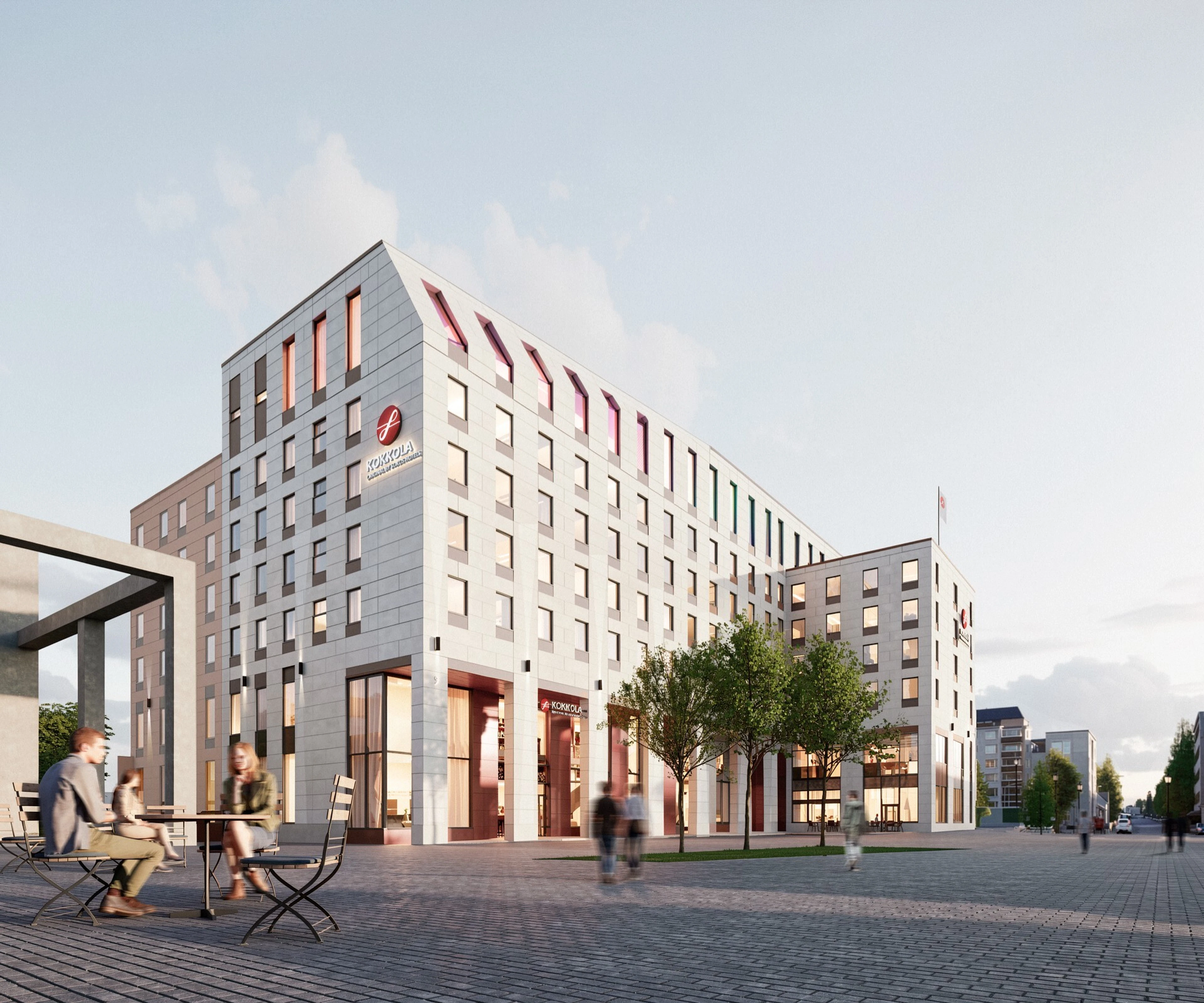Light-coloured multi-storey hotel building beside a square. The square is paved with cobblestones. Café tables and trees are in front, with people sitting and walking.
