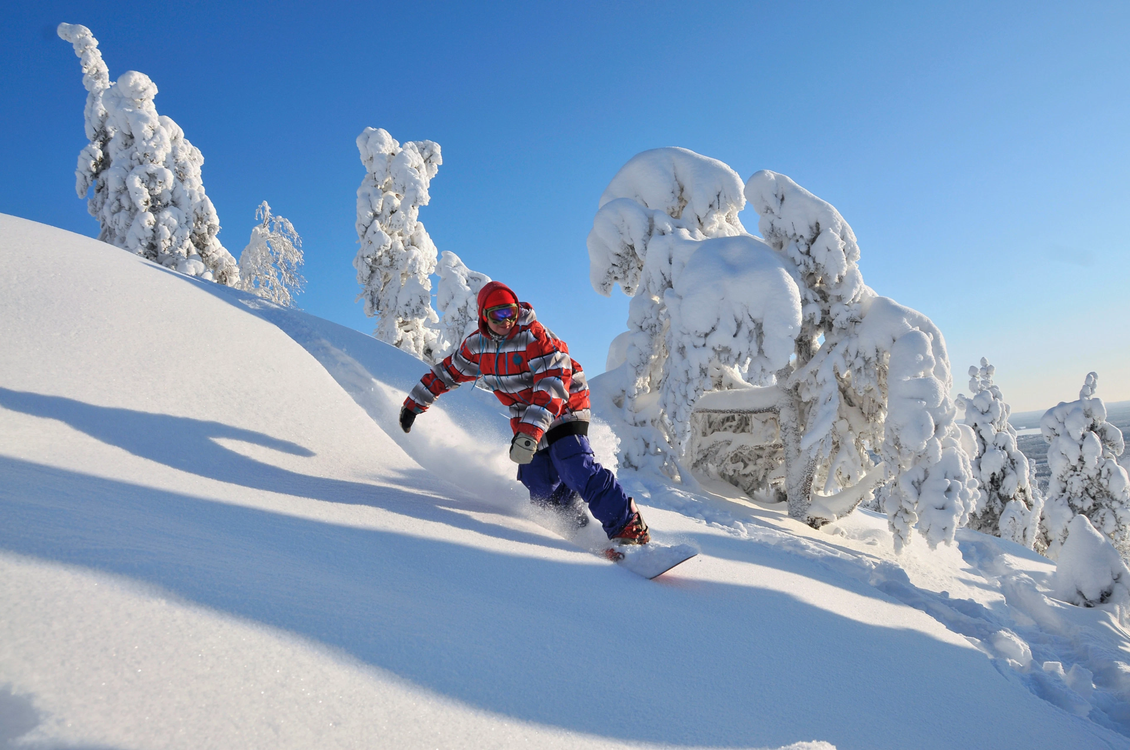 Lumilautailija laskettelee Vuokatin rinteillä aurinkoisessa talvisäässä.