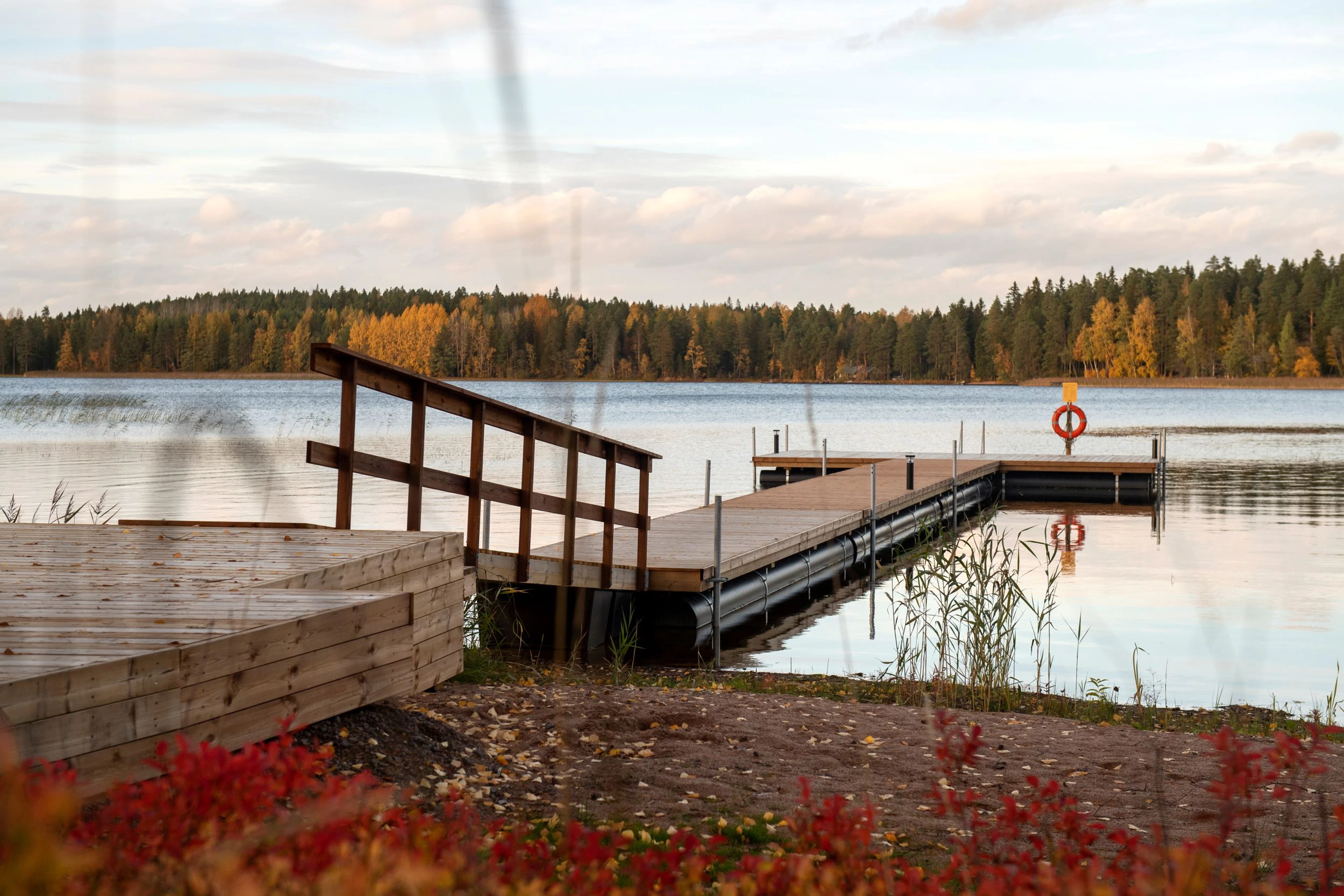 Laituri järven rannalla, vastarannan puissa syksyn värit.