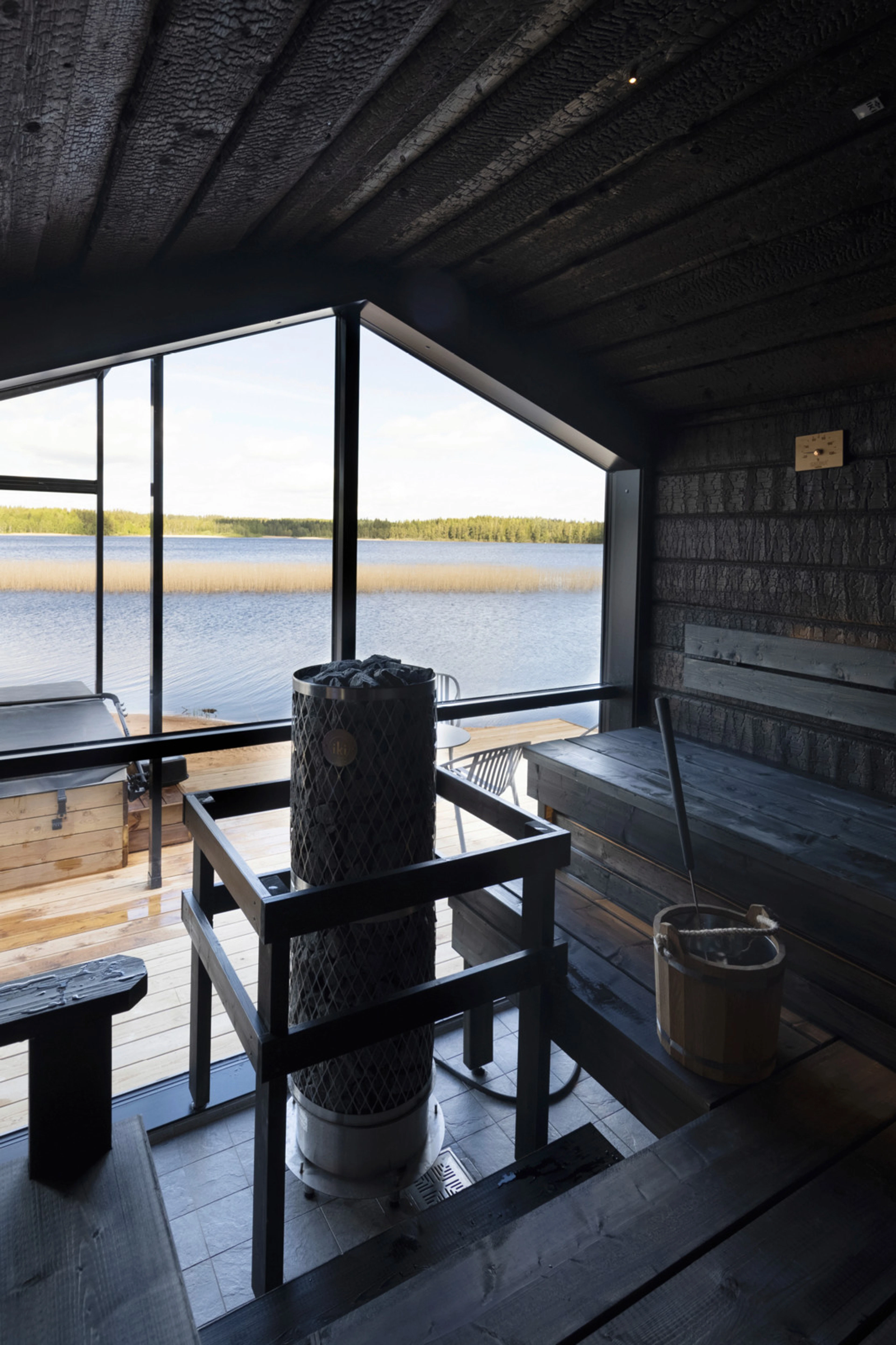 Panoraamasaunan ikkunasta näkyy terassia ja aurinkoista järvimaisemaa.